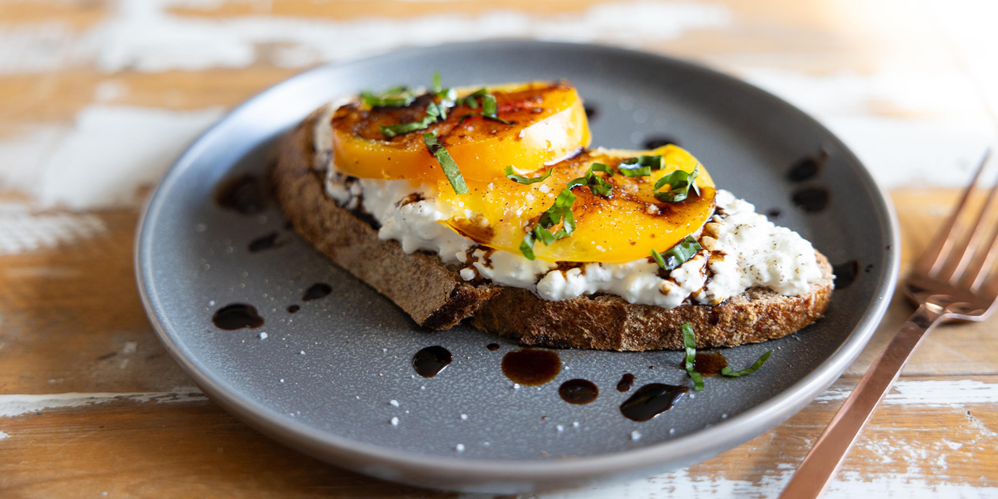 Organic cottage cheese on sourdough toast with heirloom tomatoes, salt, pepper, basil, and balsamic vinegar.