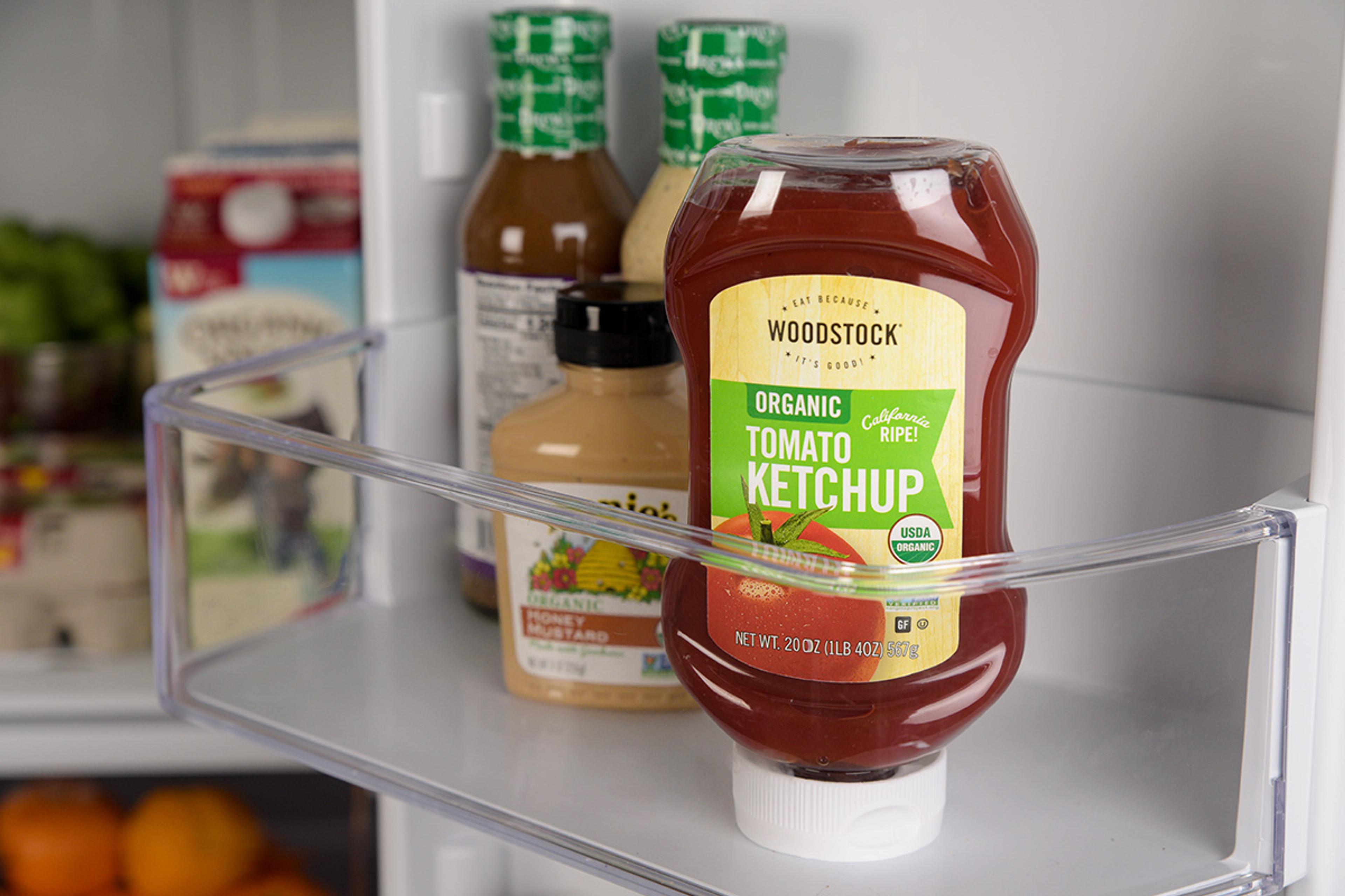Organic ketchup in the door of an open, stocked fridge.