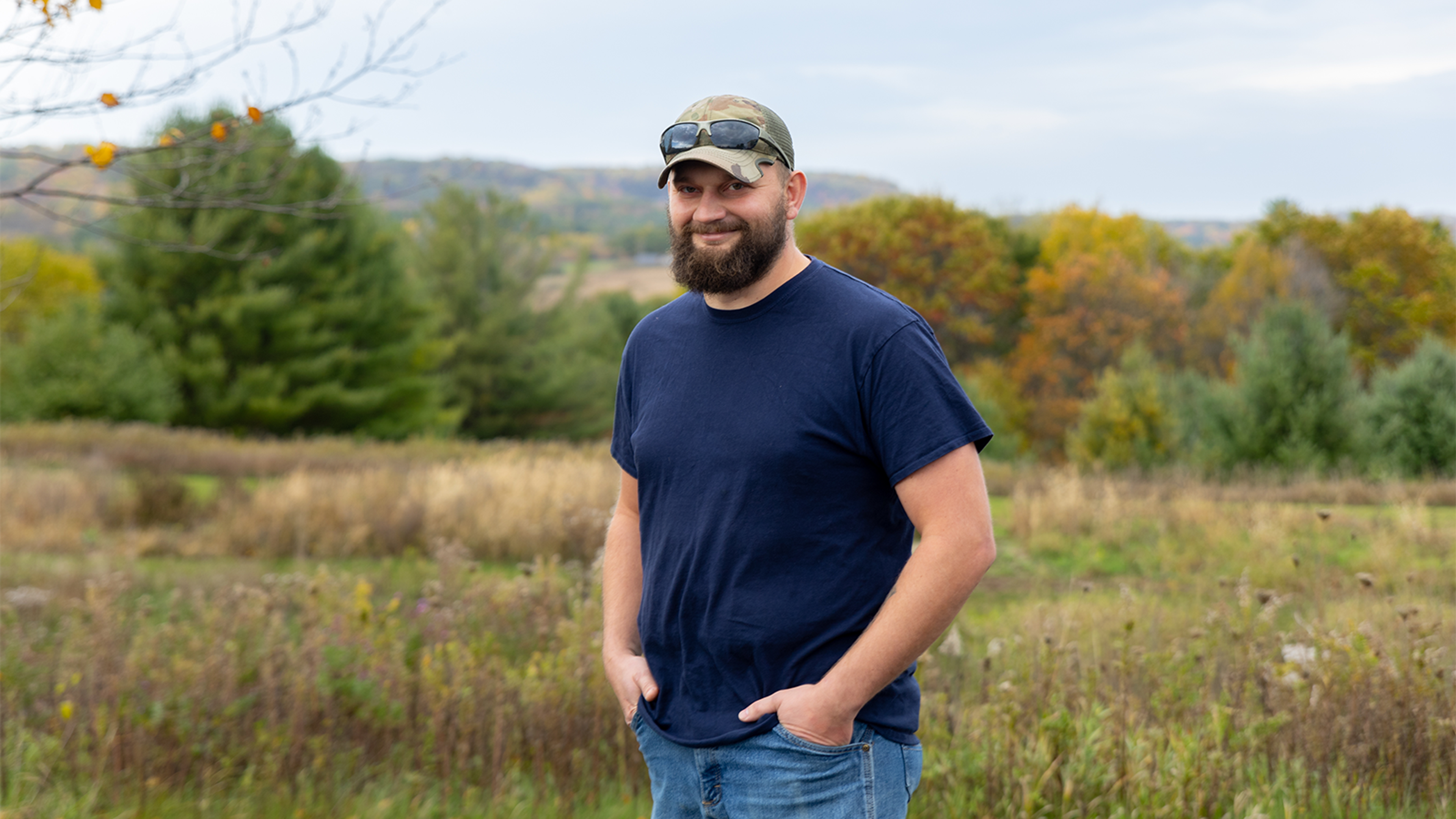 Eric Palmer stands in front of a meadow and trees in La Farge.