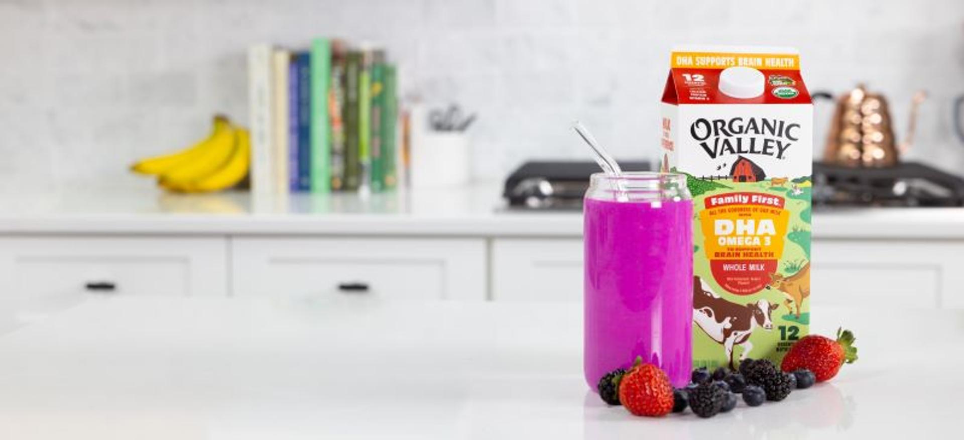 A smoothie on the kitchen counter next to a carton of milk and berries.