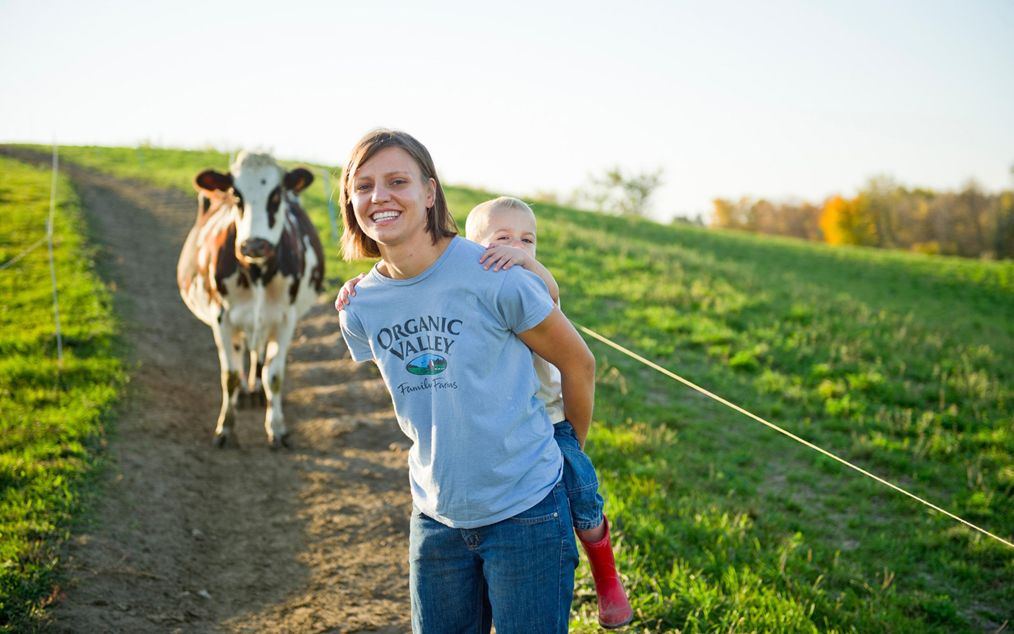 Emily Zweber gives her son a piggyback ride while leading a cow back to the barn.