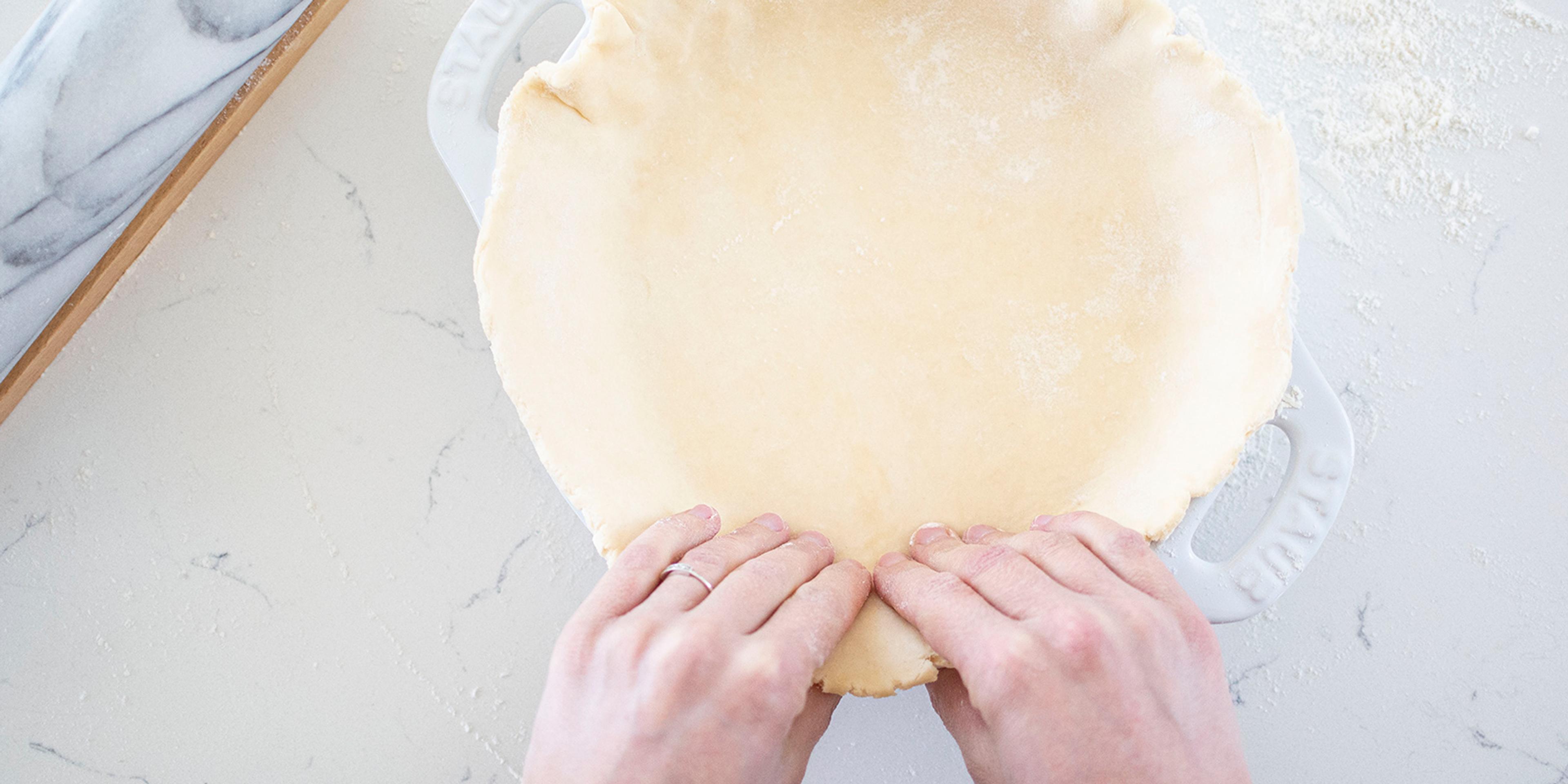 Hands shaping an all-butter pie crust into a pan. Mimi Council photo