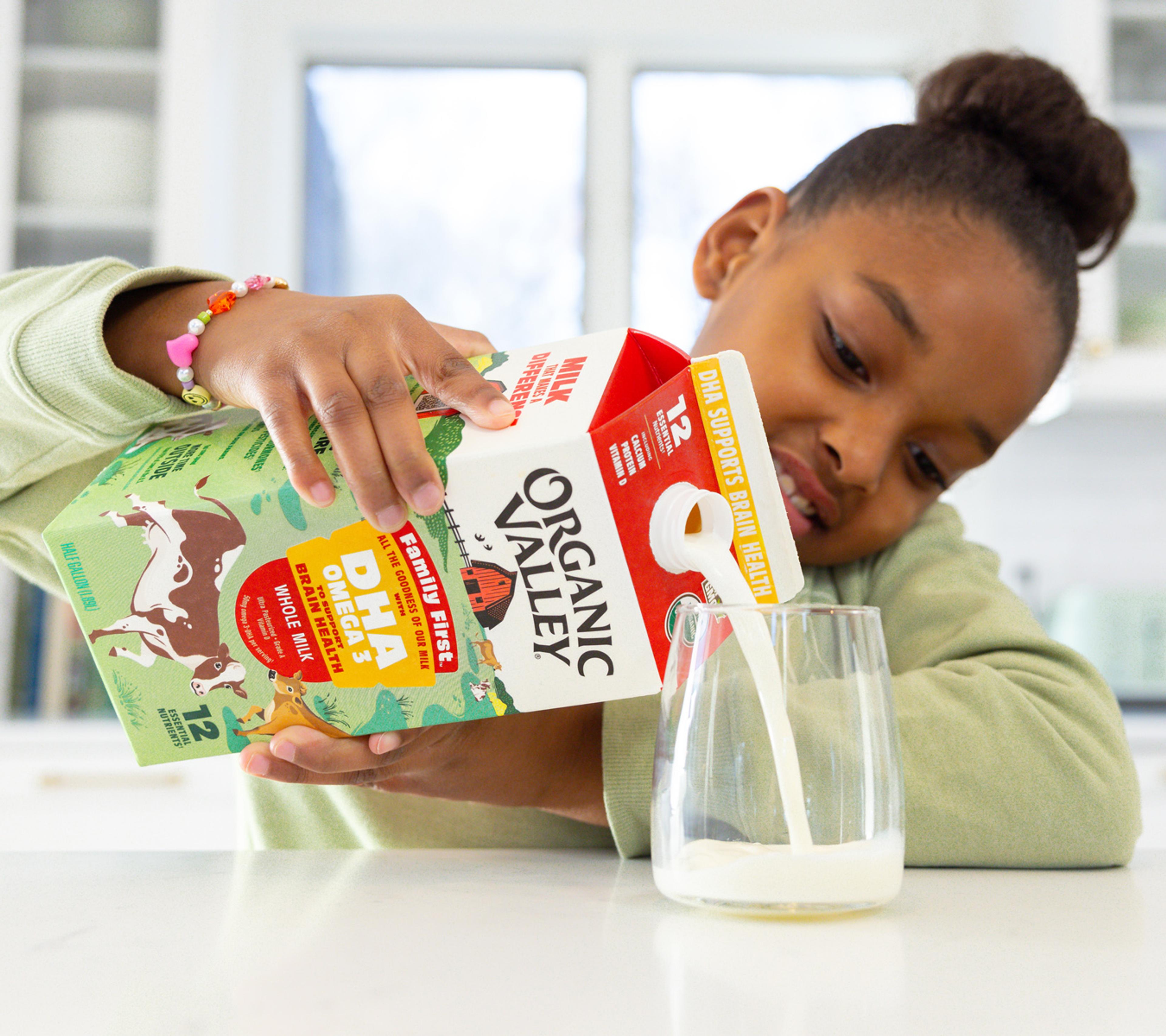 young girl pouring a glass of organic valley family first DHA omega 3 whole milk