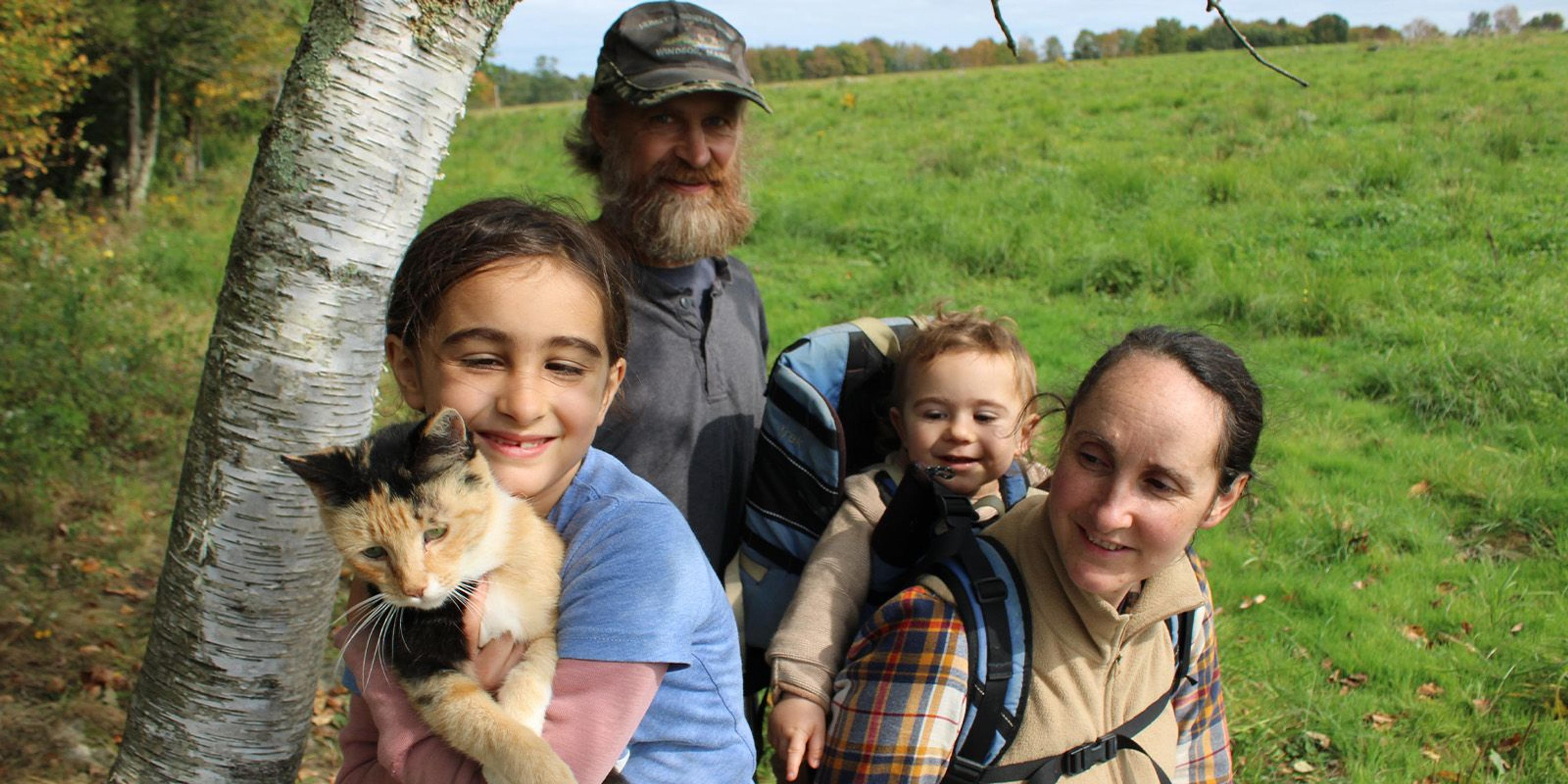 Four members of the Clark, Webb Clark family pose and a girl holds a cat on their Maine farm.