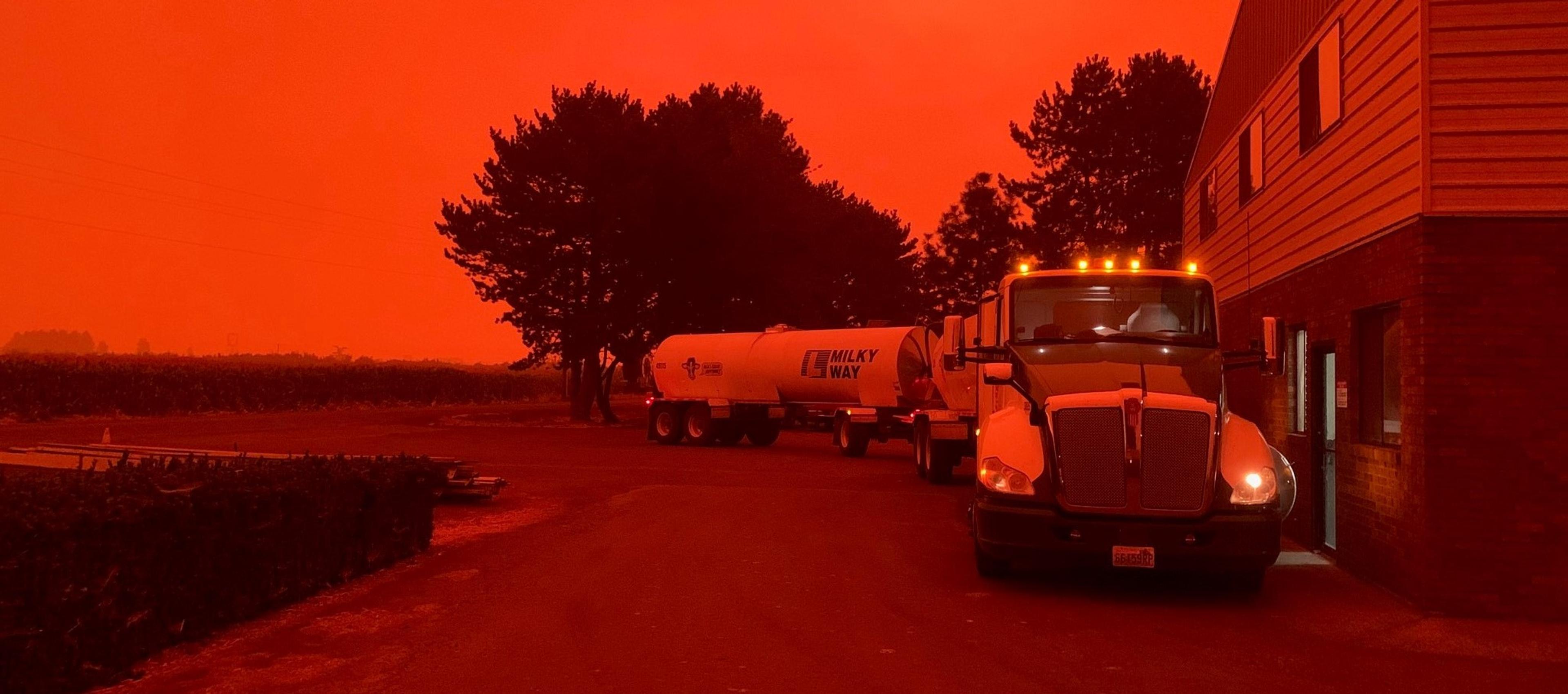 The sky is red from wildfires in this 2021 photo of a milk truck. 