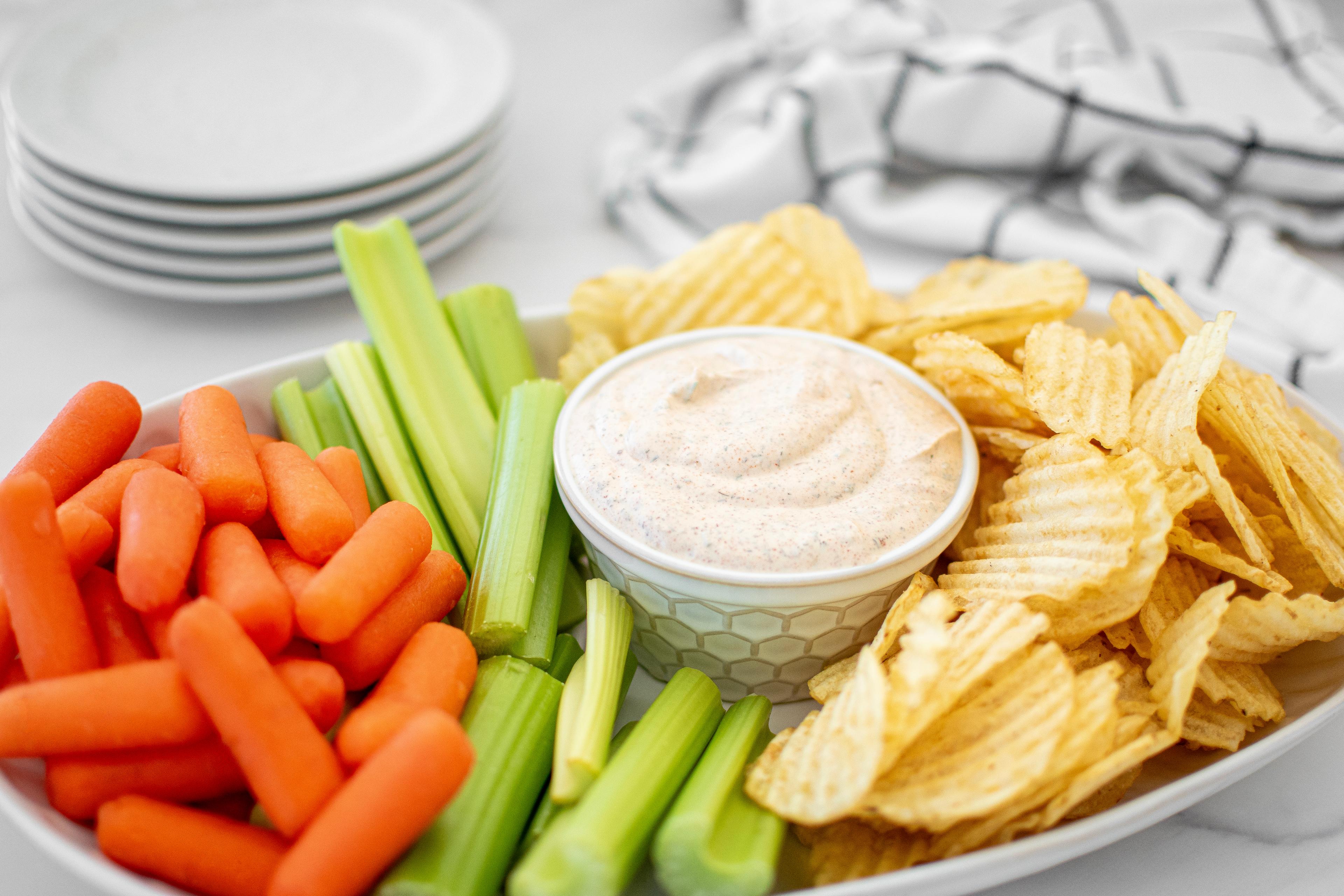 Buffalo Ranch Dip with chips, celery and carrots on a serving dish.