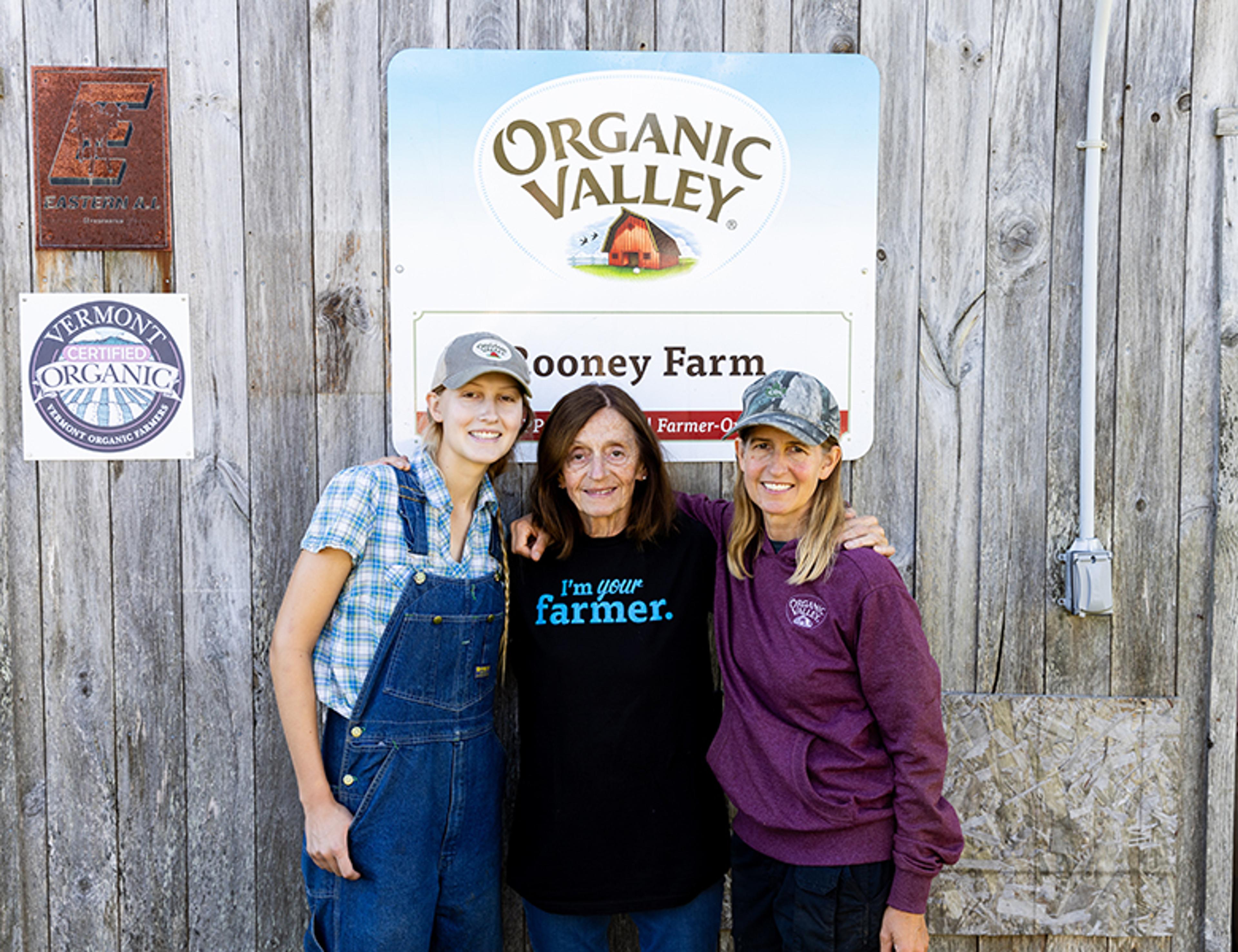 Rooney farmers stand in front of Organic Valley barn sign.