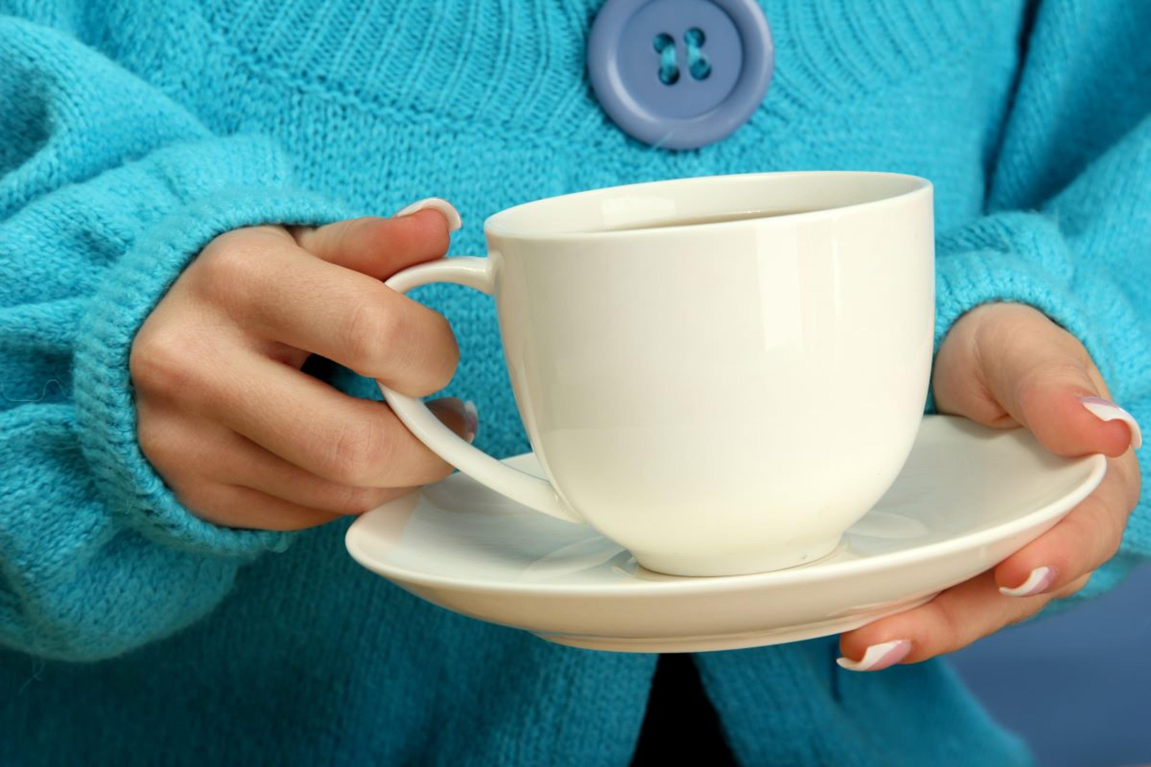 A woman holds a cup of coffee.