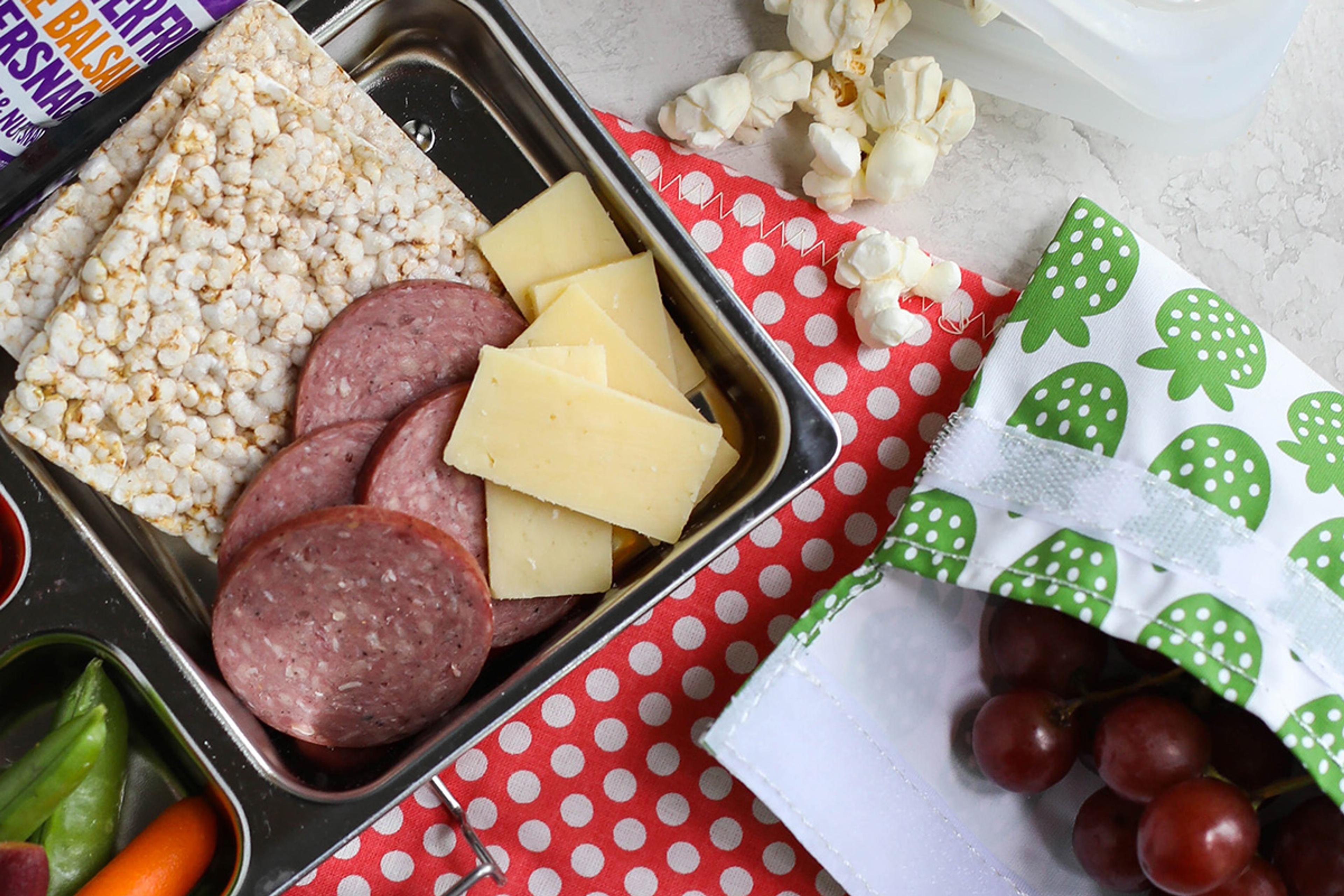 A packed lunchbox with organic summer sausage and other snacks.