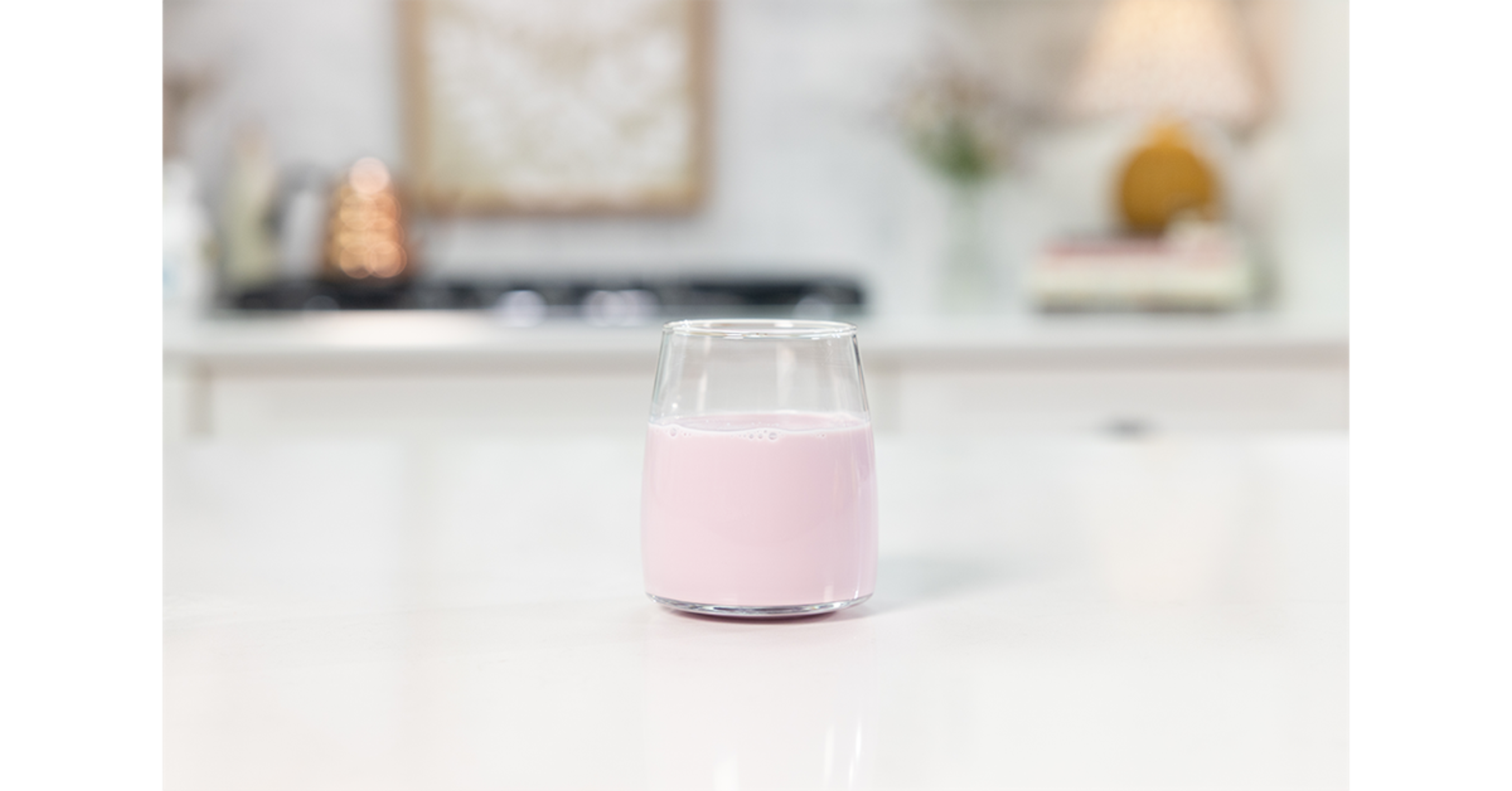 Aronia juice and milk stirred in a short glass in a kitchen.