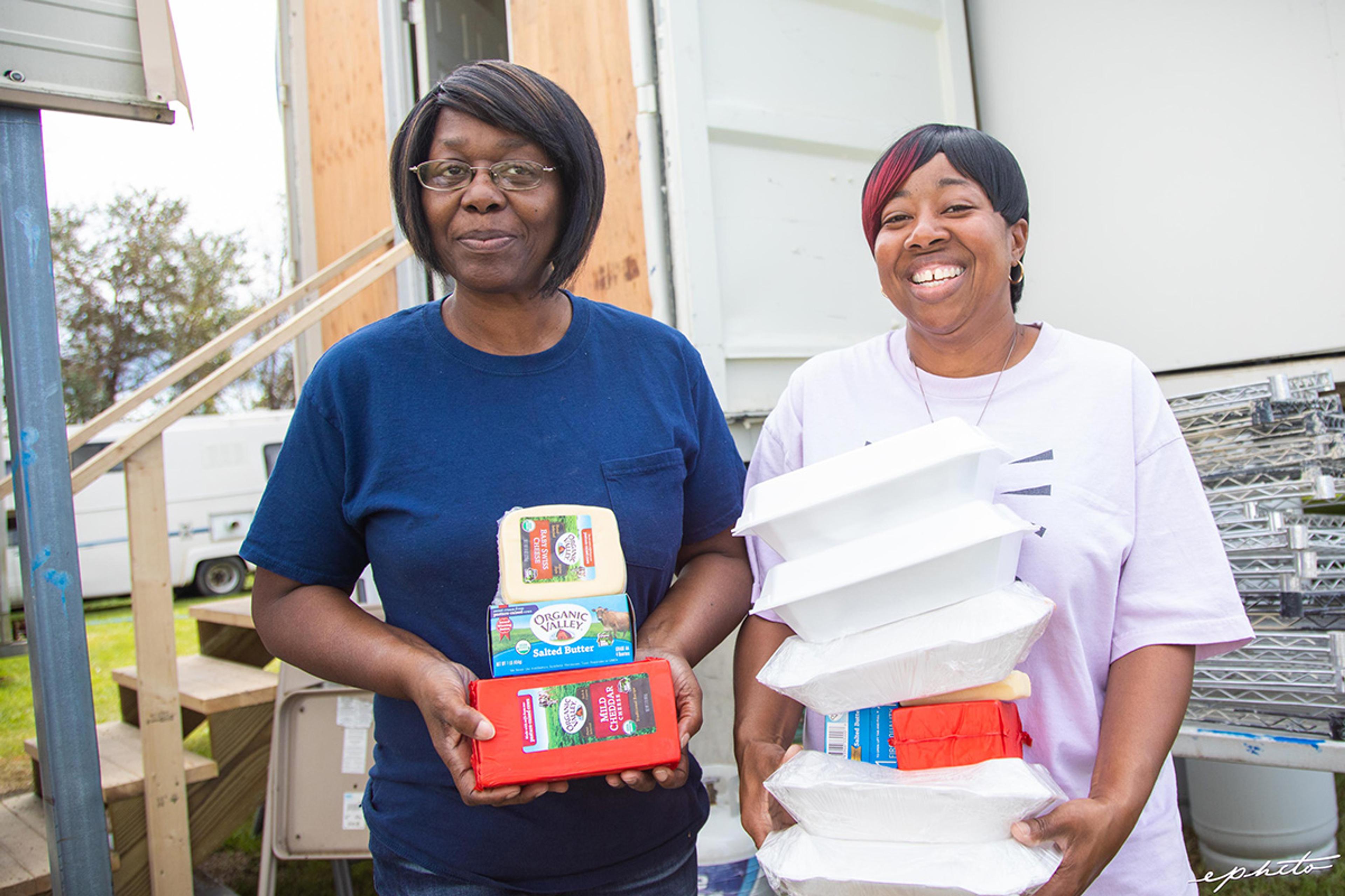 Two women hold packages of Organic Valley cheese and other food.