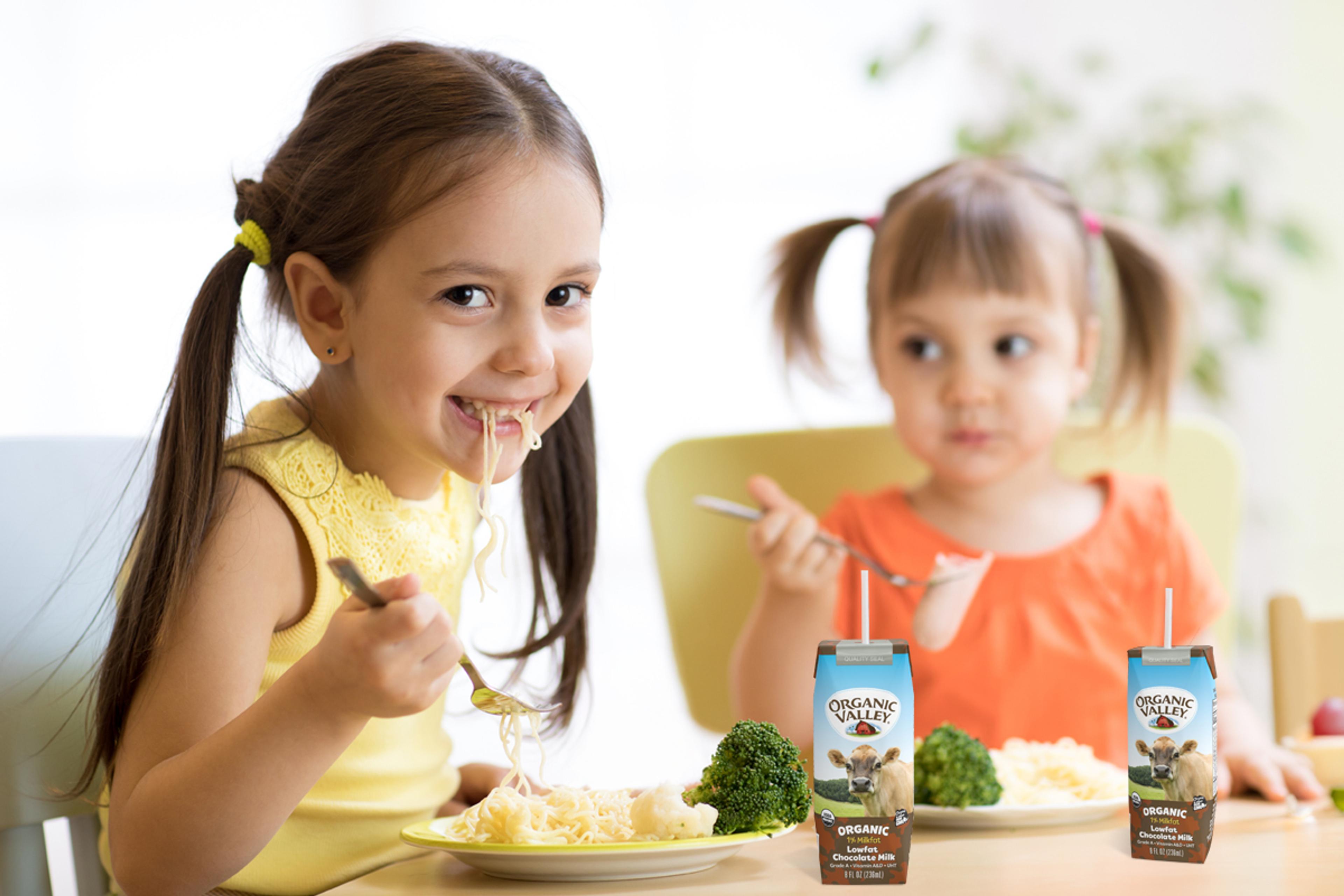 2 girls with single-serve milk boxes on the table.