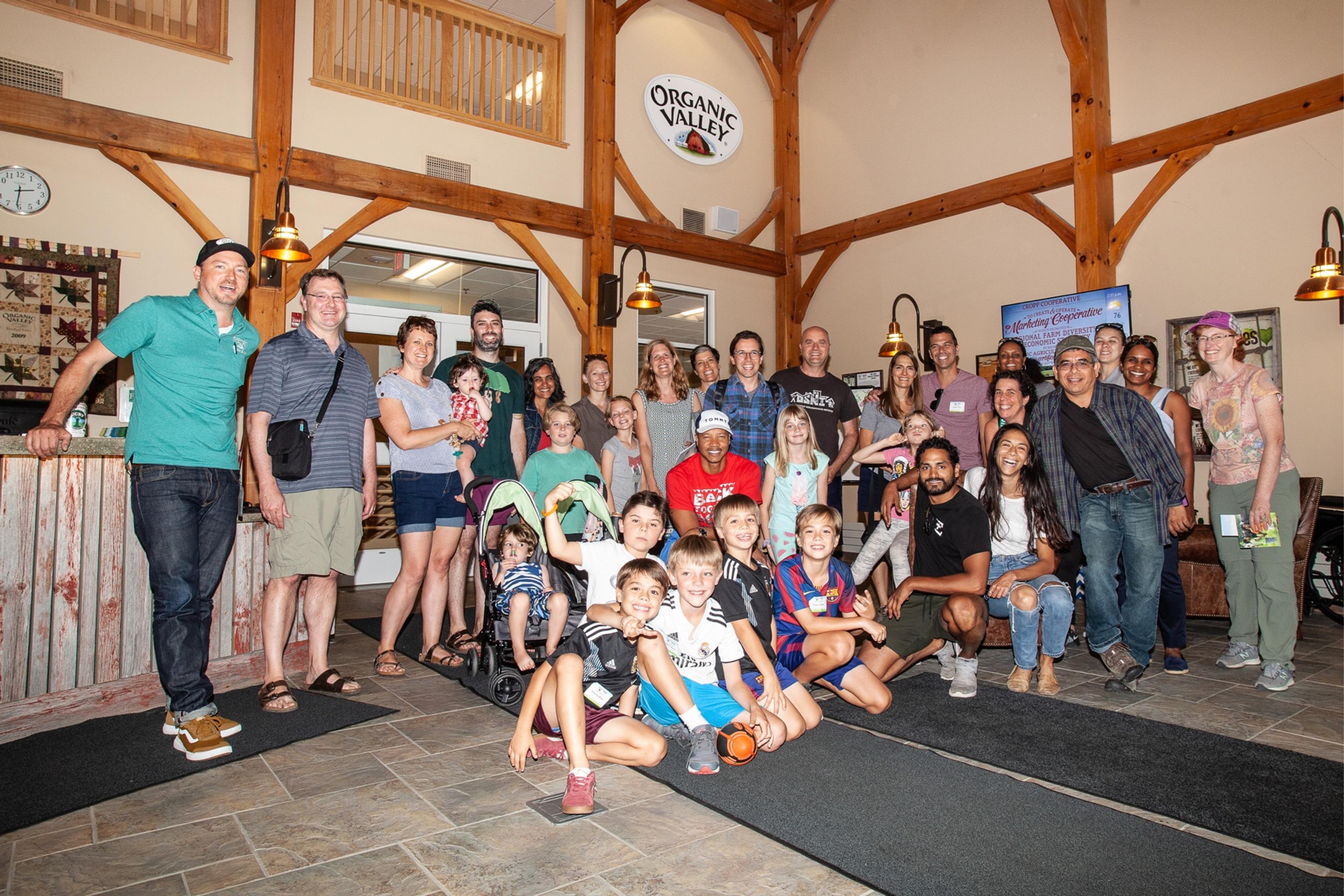 A large group of men, women and children pose in the Organic Valley office building lobby.