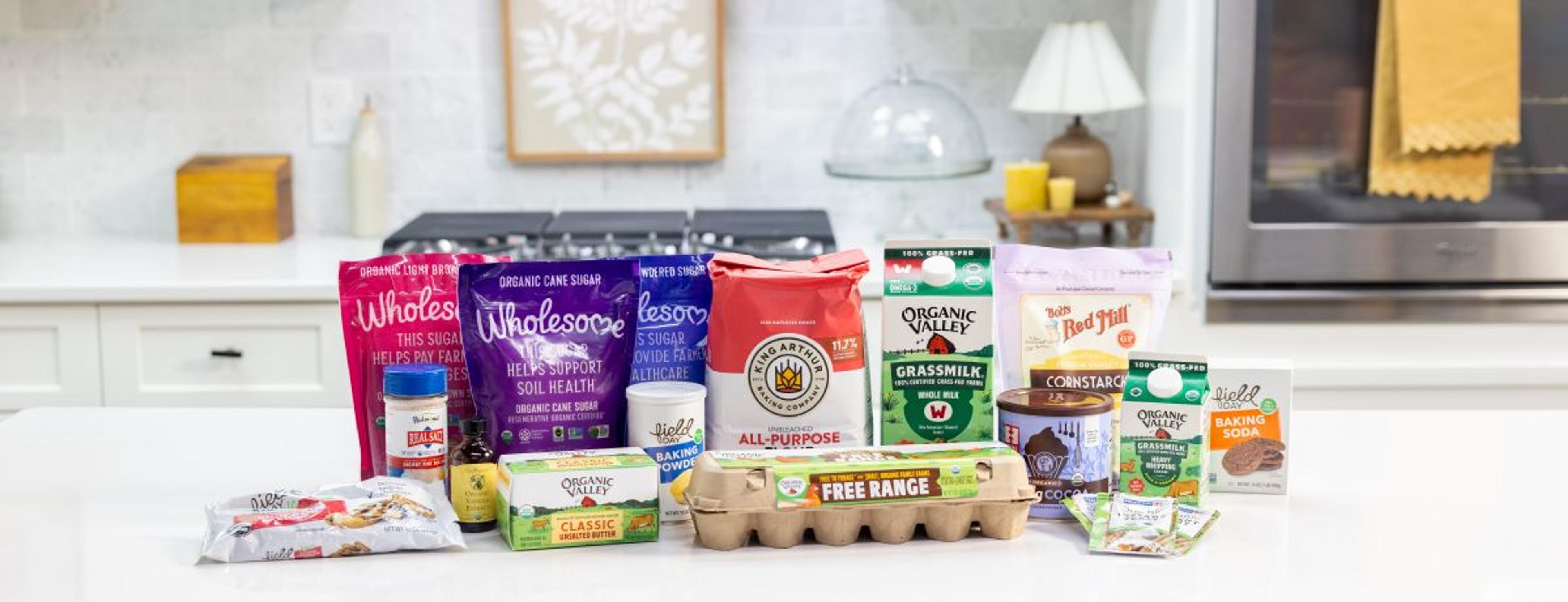  Yeast, baking cocoa, chocolate chips, corn starch, organic eggs, powdered sugar and more on a white counter. 