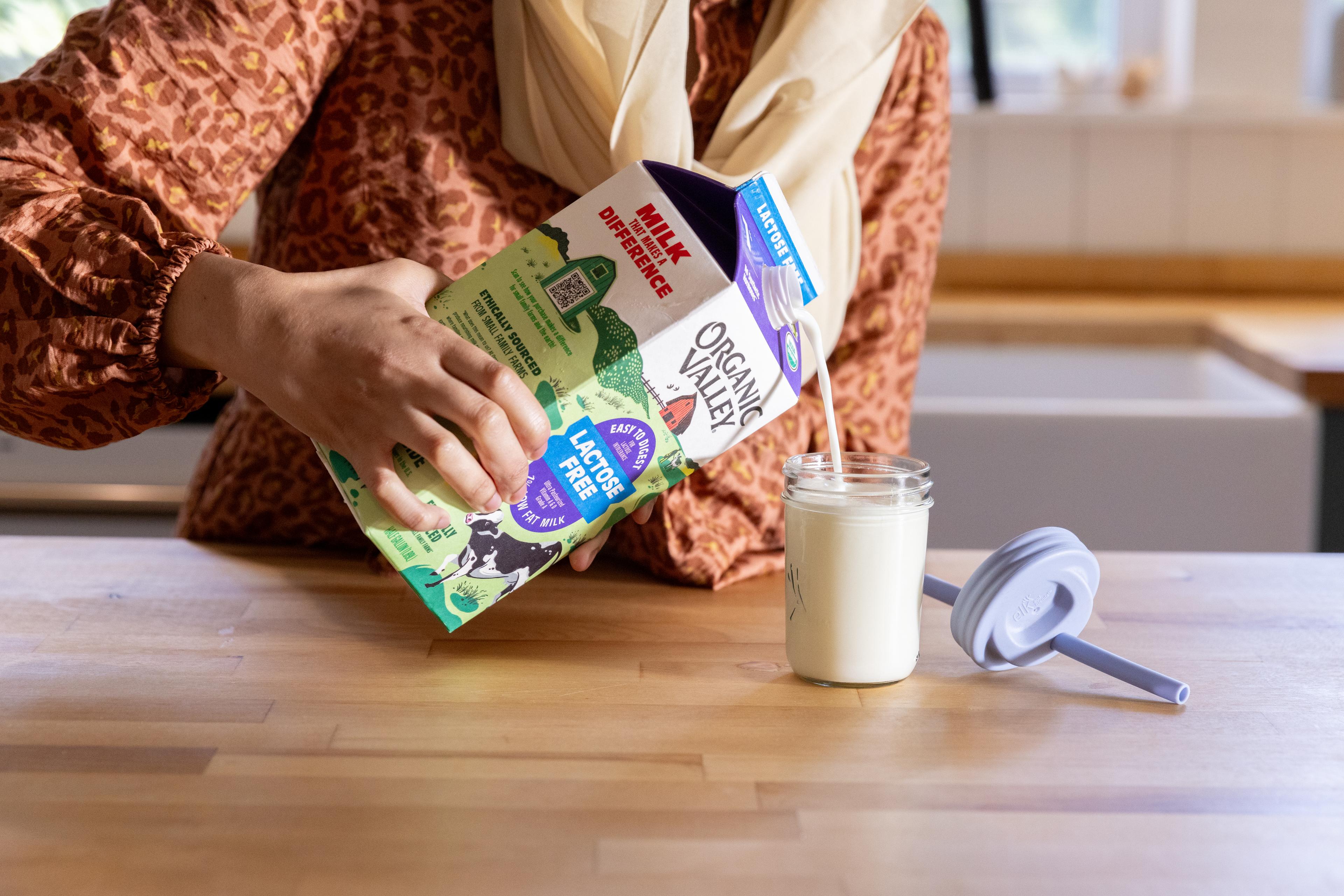 A woman pours Organic Valley lowfat lactose-free milk in a child's cup.