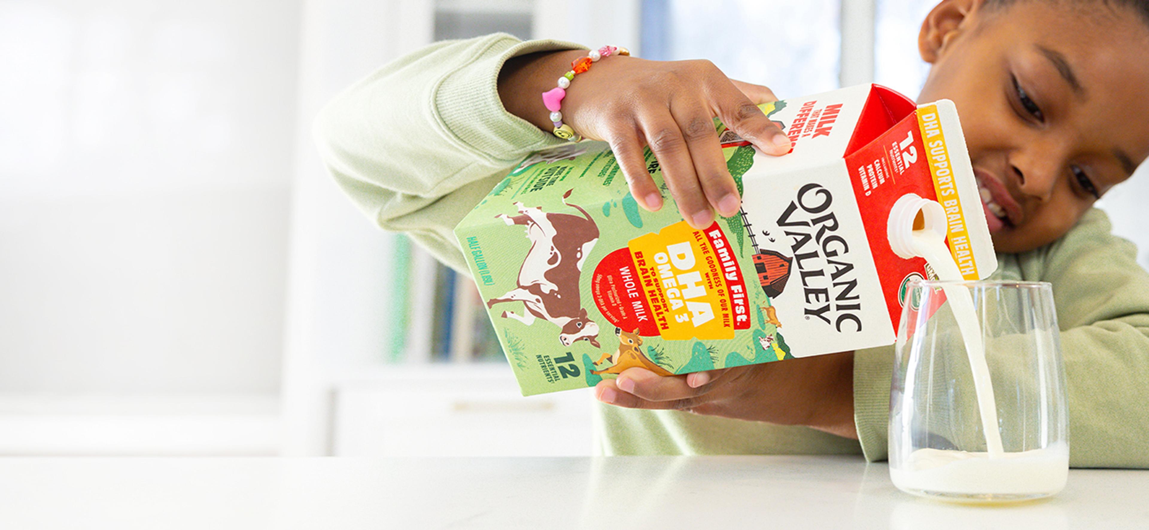 Girl pours a glass of Organic Valley Family First DHA Omega 3 milk.