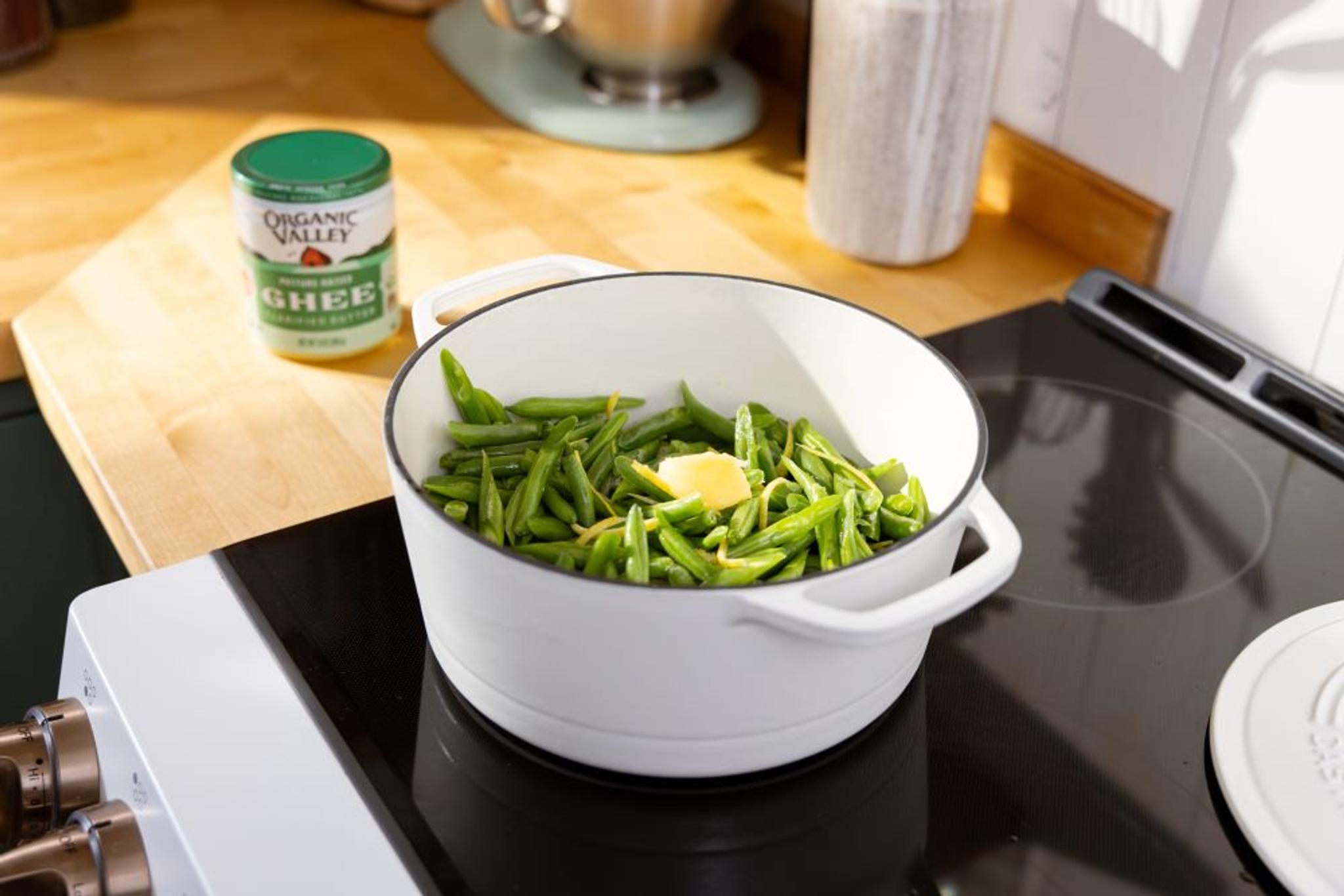 Organic ghee next to a pan of greenbeans.