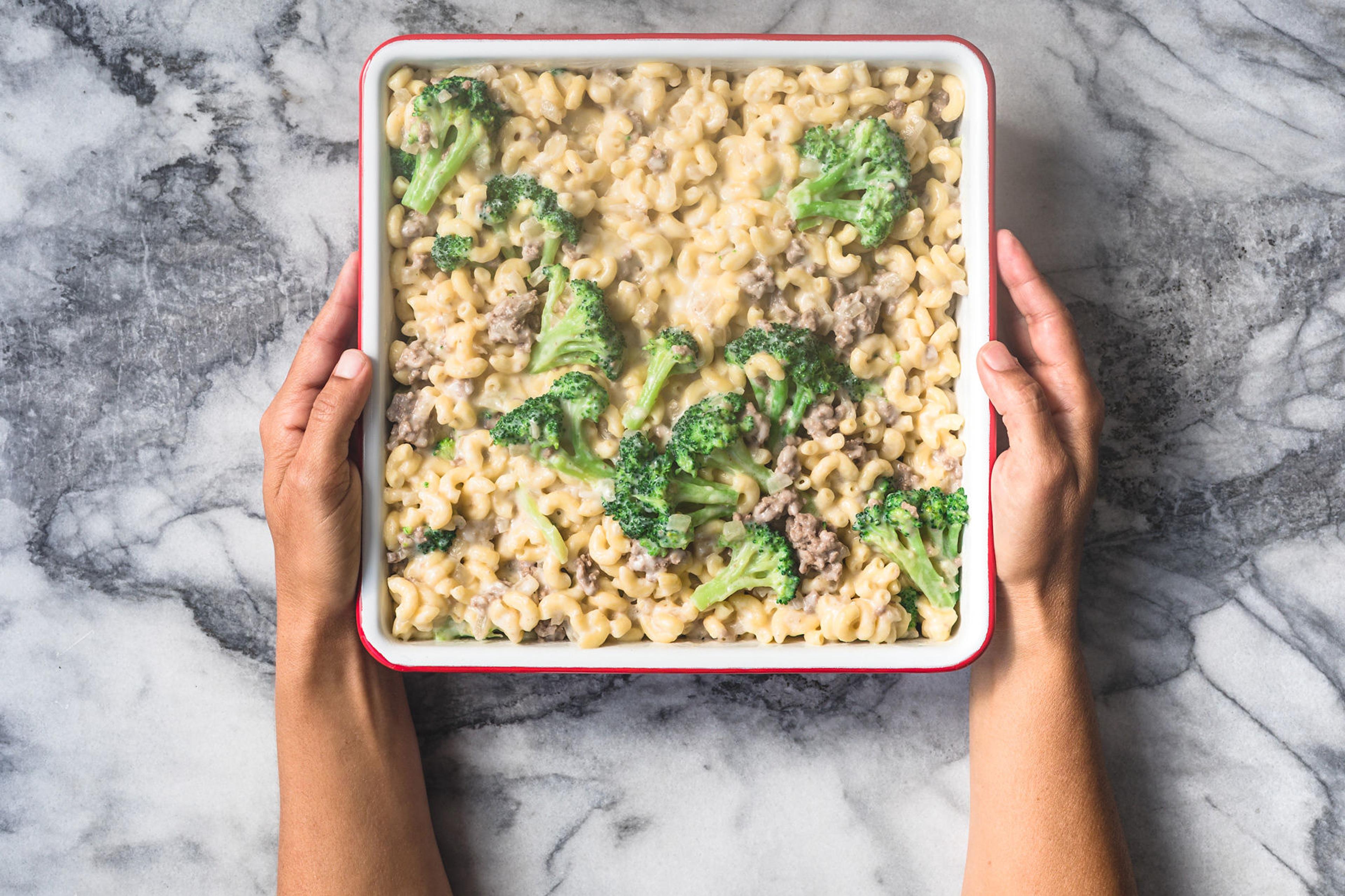 Baked mac and cheese with meat and vegetables being served onto a plate. Photo by Daniela Gerson.