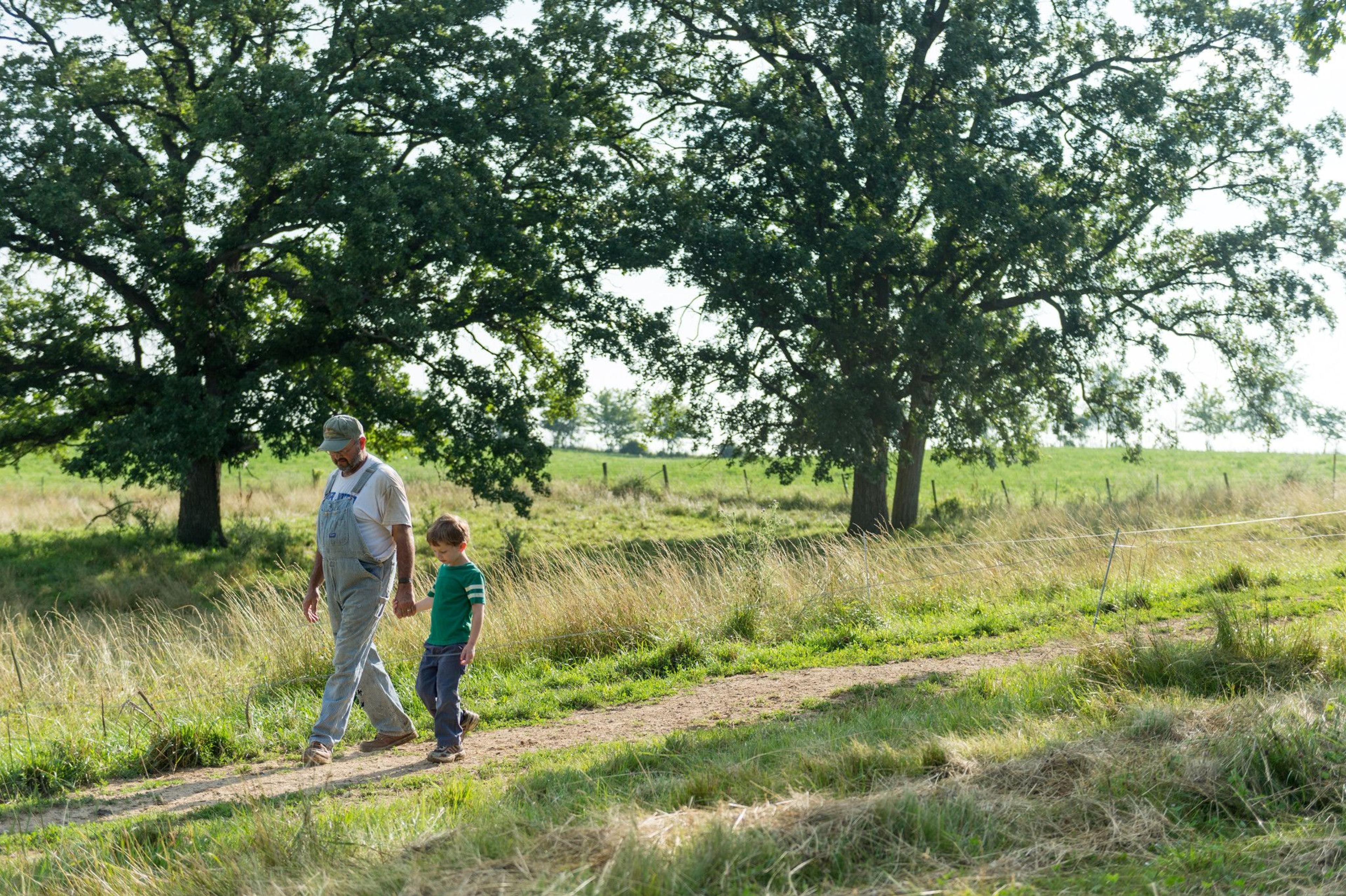 A man and boy walk a path surrounded by trees.