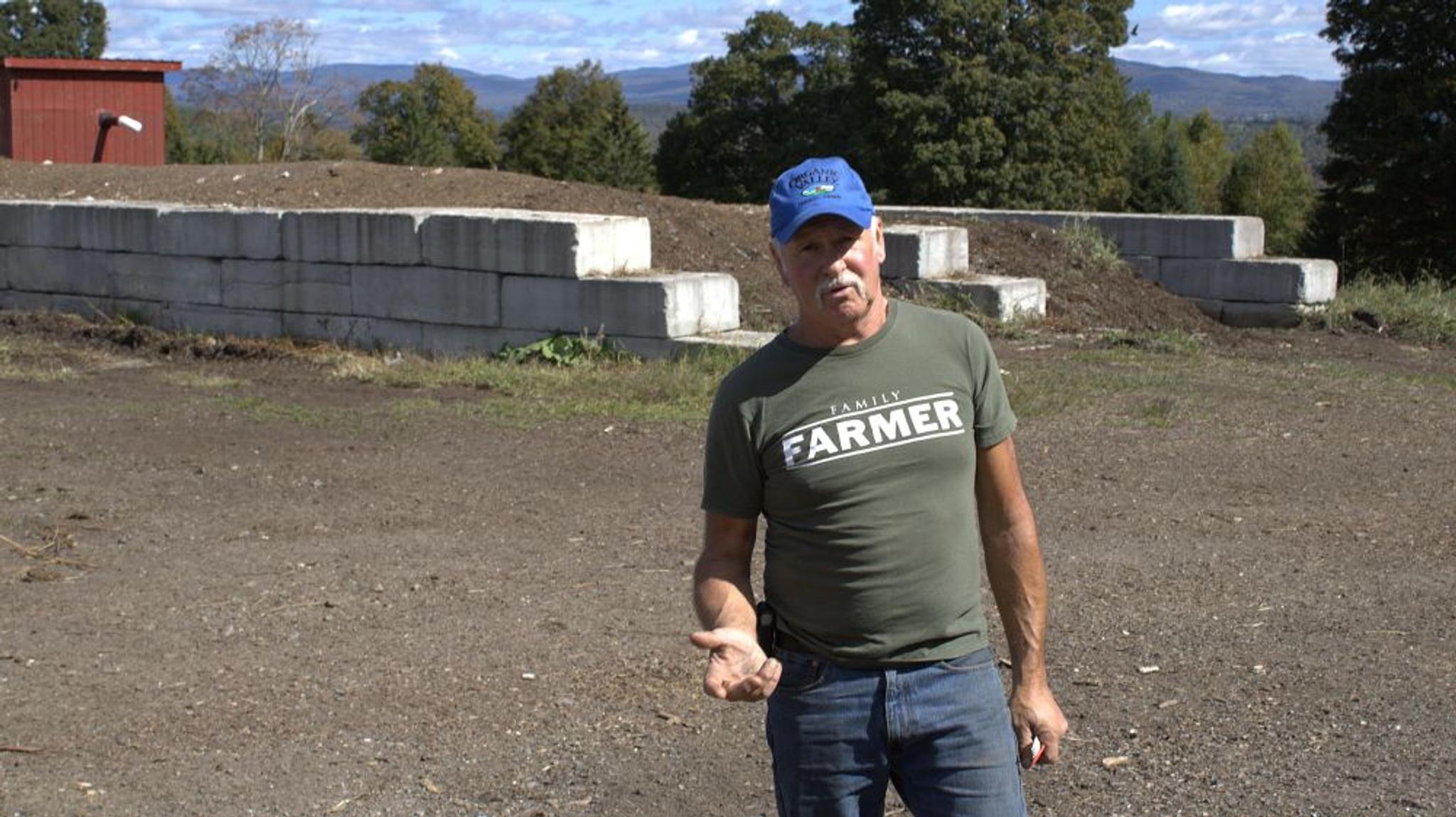 Eric stands in front of compost from food waste that is separated by stone walls.