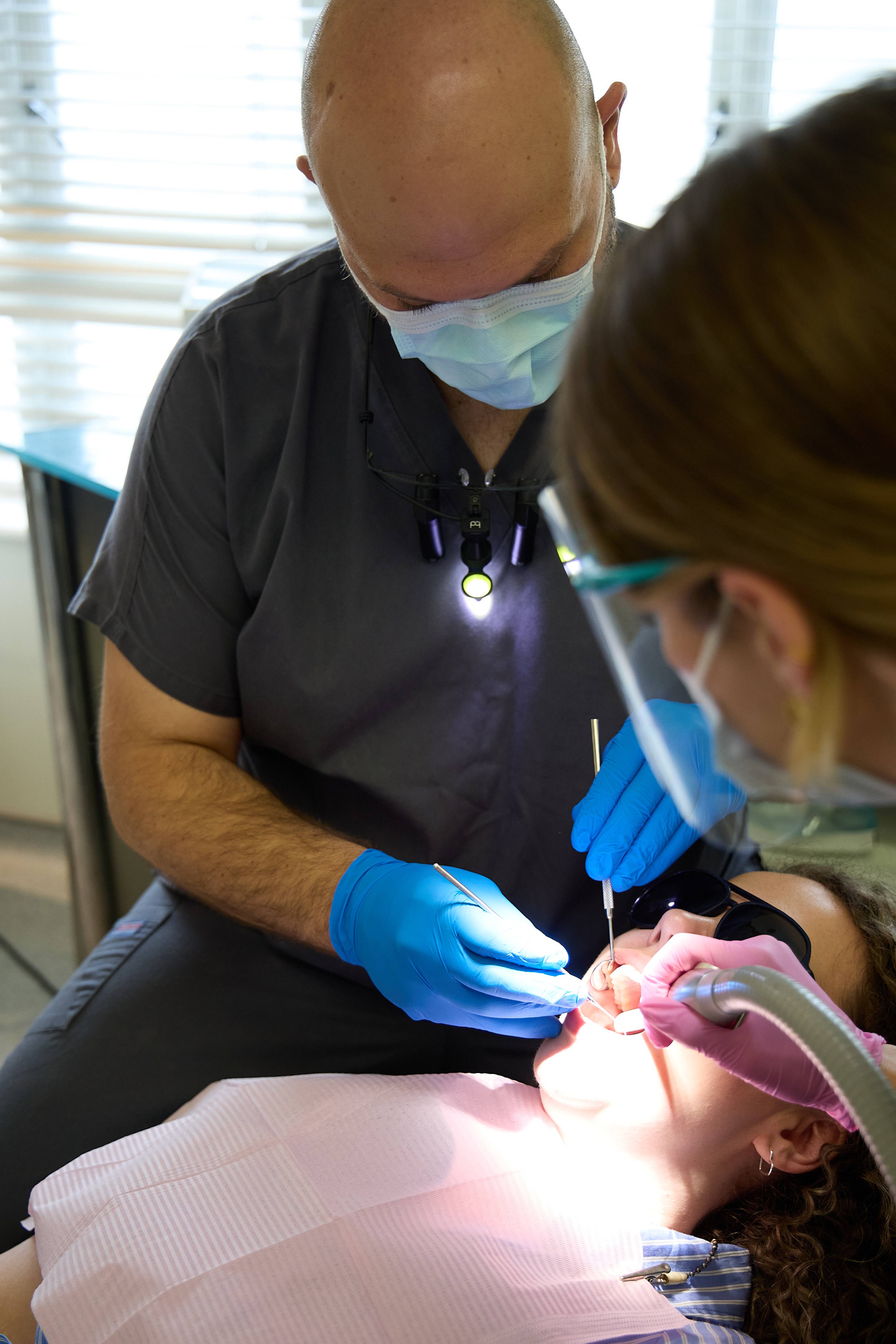 Dental team providing treatment to a patient using modern clinical instruments and suction equipment at Bath Spa Dentistry.