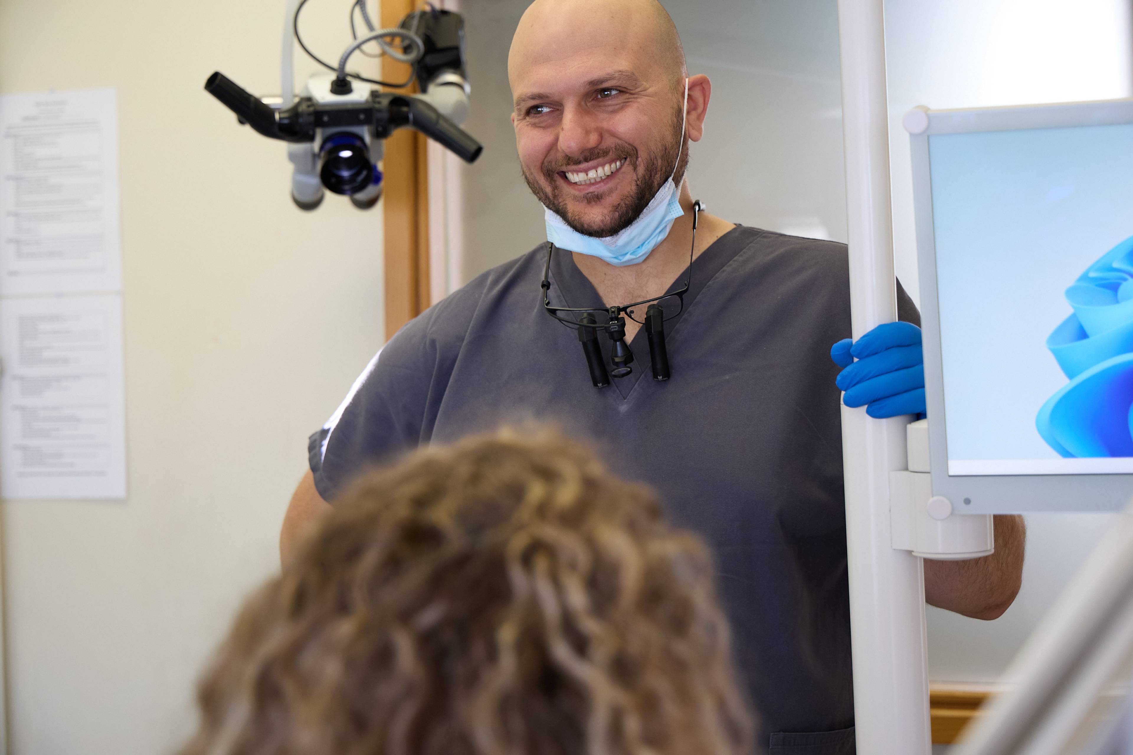 Dental professional in a modern treatment room speaking with a patient during a consultation.