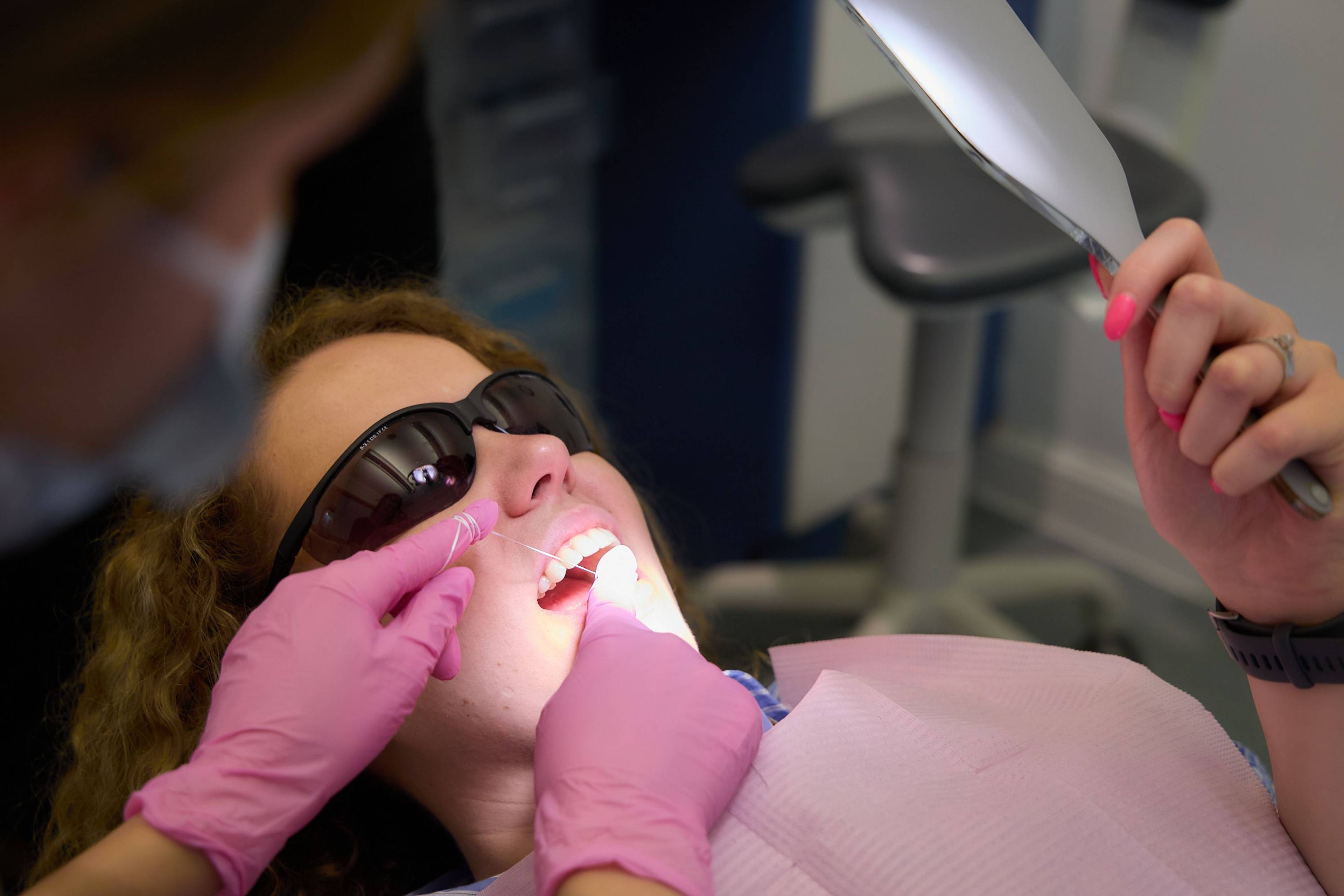 Patient holding a hand mirror while receiving a dental examination at Bath Spa Dentistry.