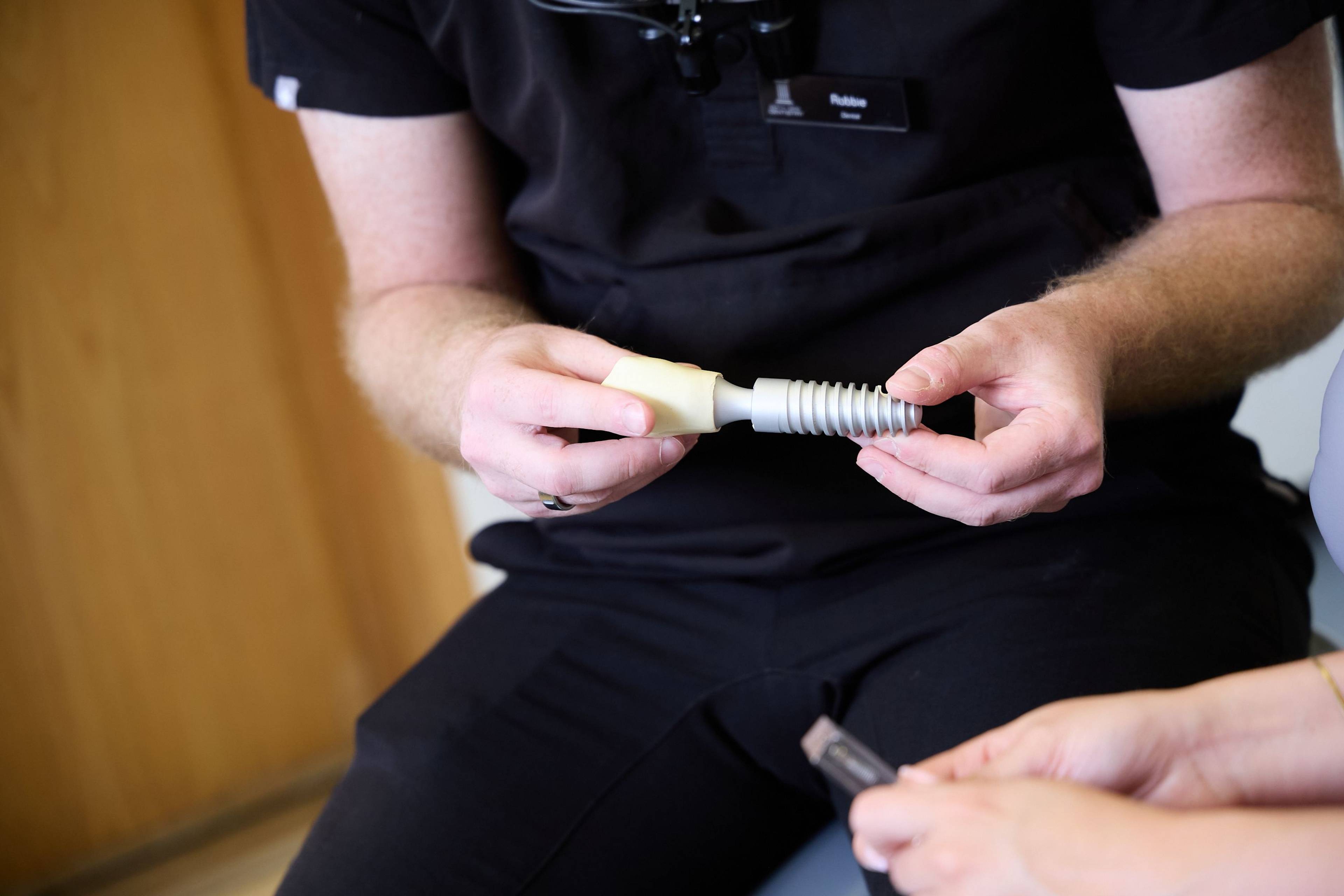 Dentist using a dental implant model to explain implant treatment and missing tooth replacement during a consultation at Bath Spa Dentistry.