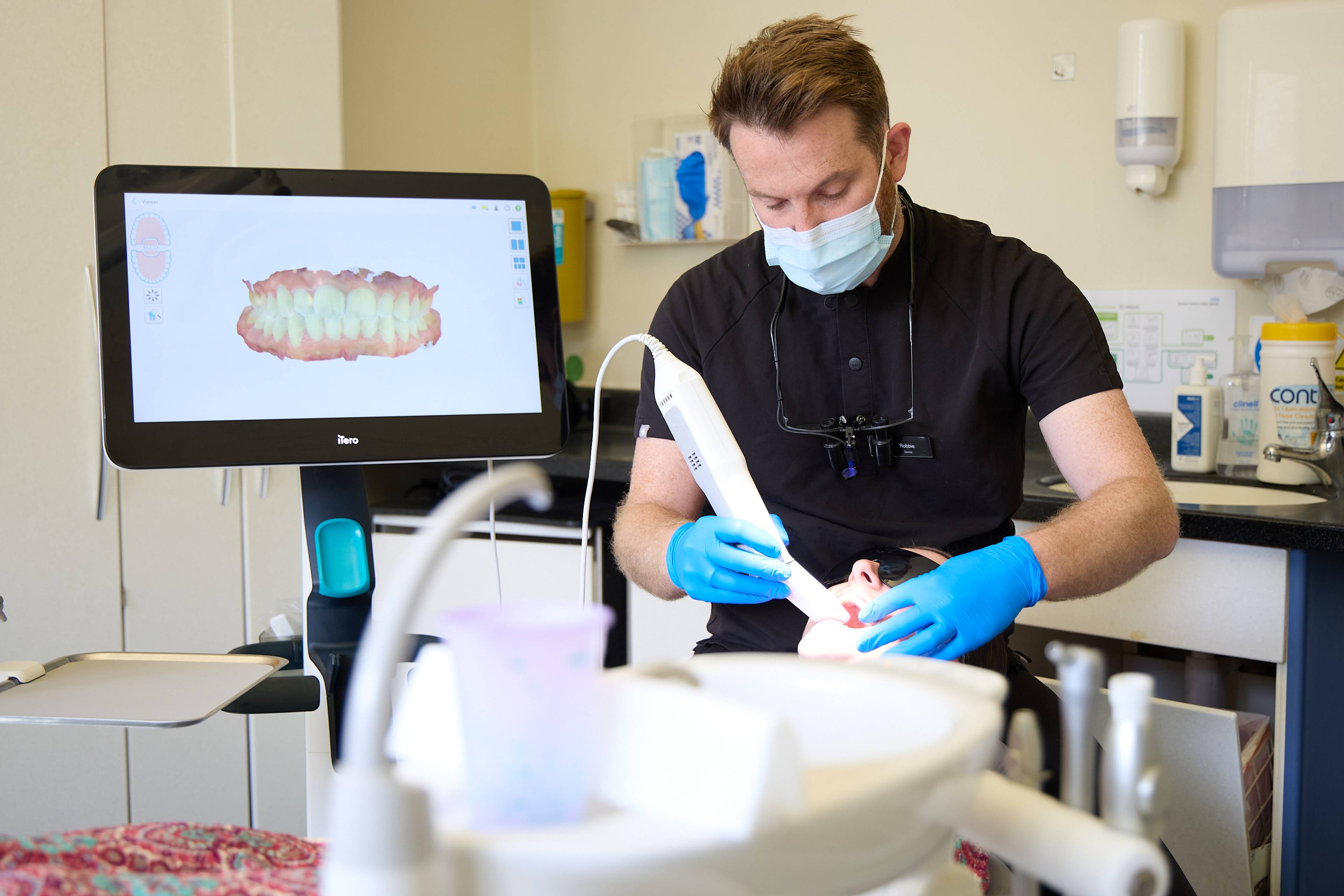 Dental team providing treatment to a patient using advanced clinical instruments and suction equipment at Bath Spa Dentistry.
