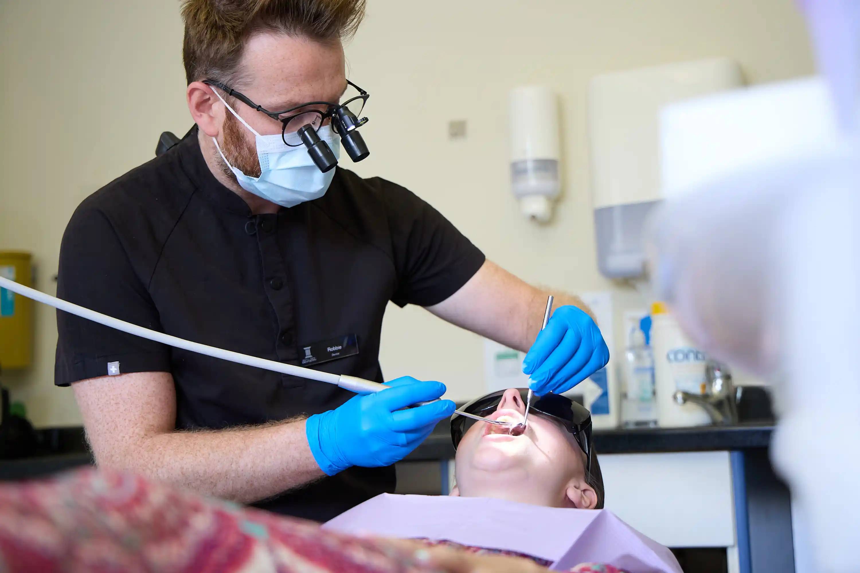 Dental professional carrying out a comprehensive oral examination in a modern treatment room.