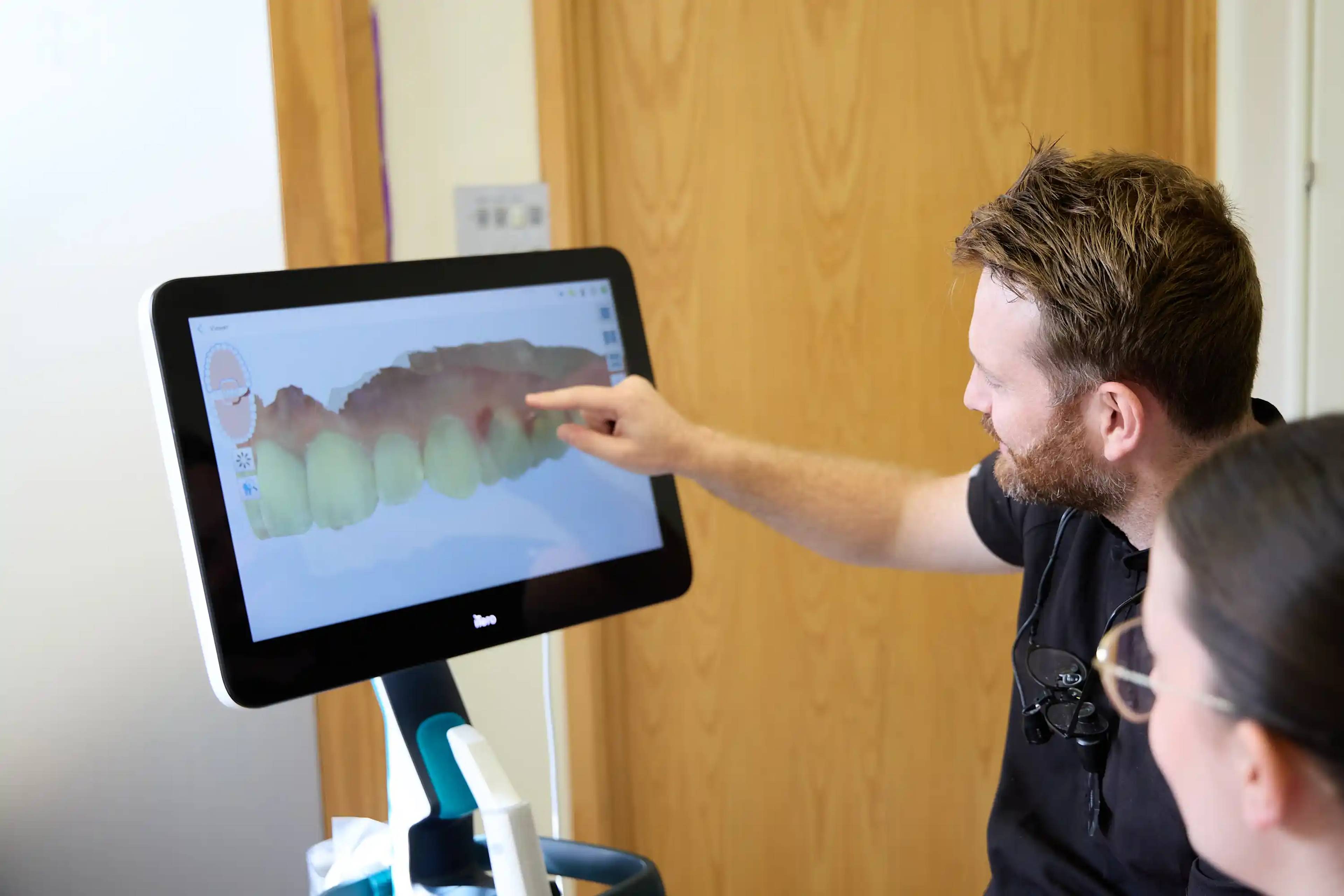 Patient undergoing a dental procedure while using a hand mirror to view treatment progress at Bath Spa Dentistry.