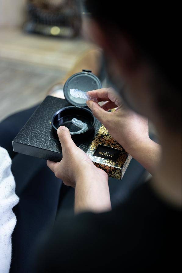 Patient holding a custom teeth whitening tray and Boutique Whitening night treatment kit during a home whitening consultation at Bath Spa Dentistry.