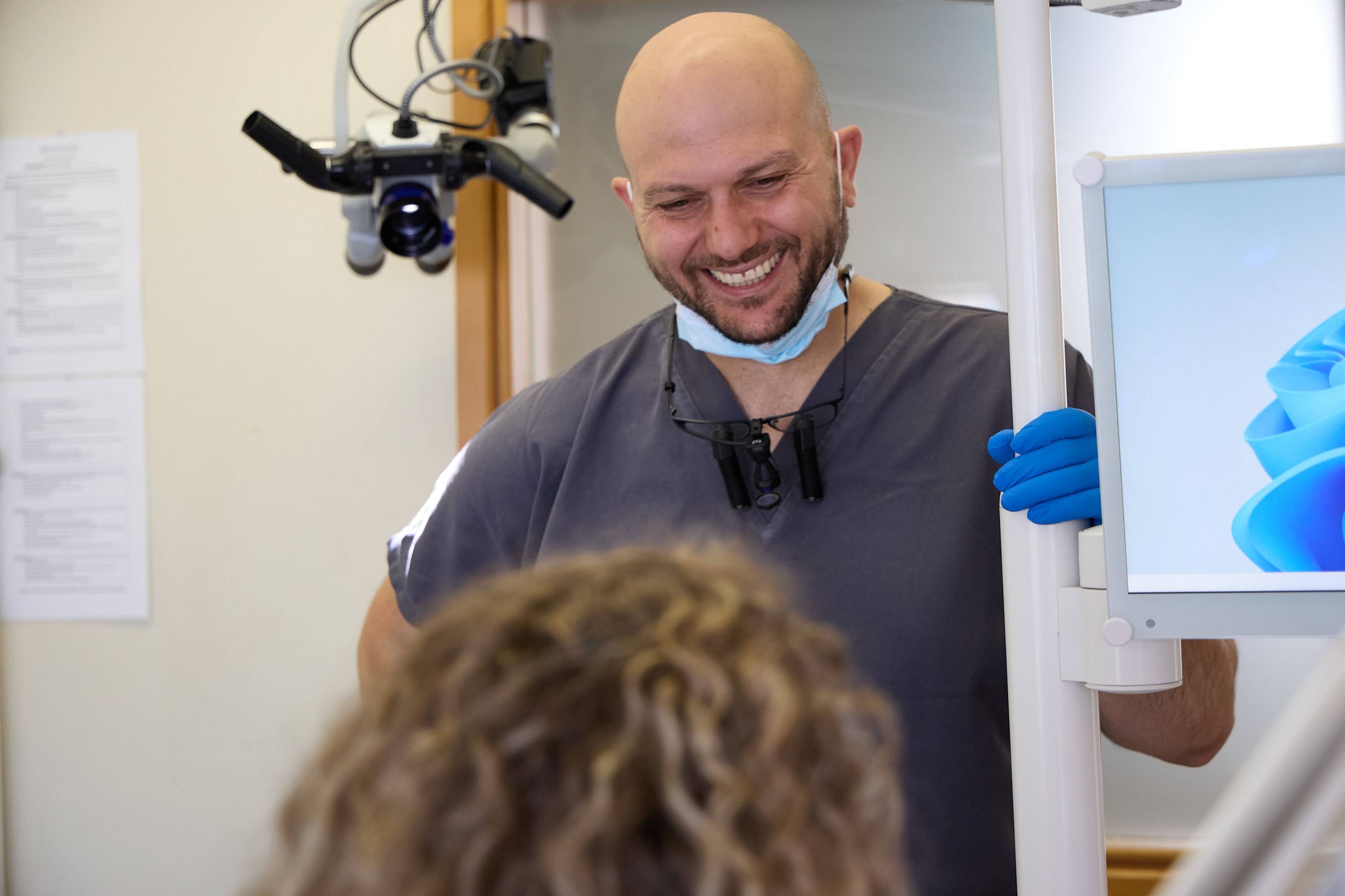 Dentist consulting with a patient in a modern treatment room at Bath Spa Dentistry, using advanced magnification technology and digital imaging equipment.