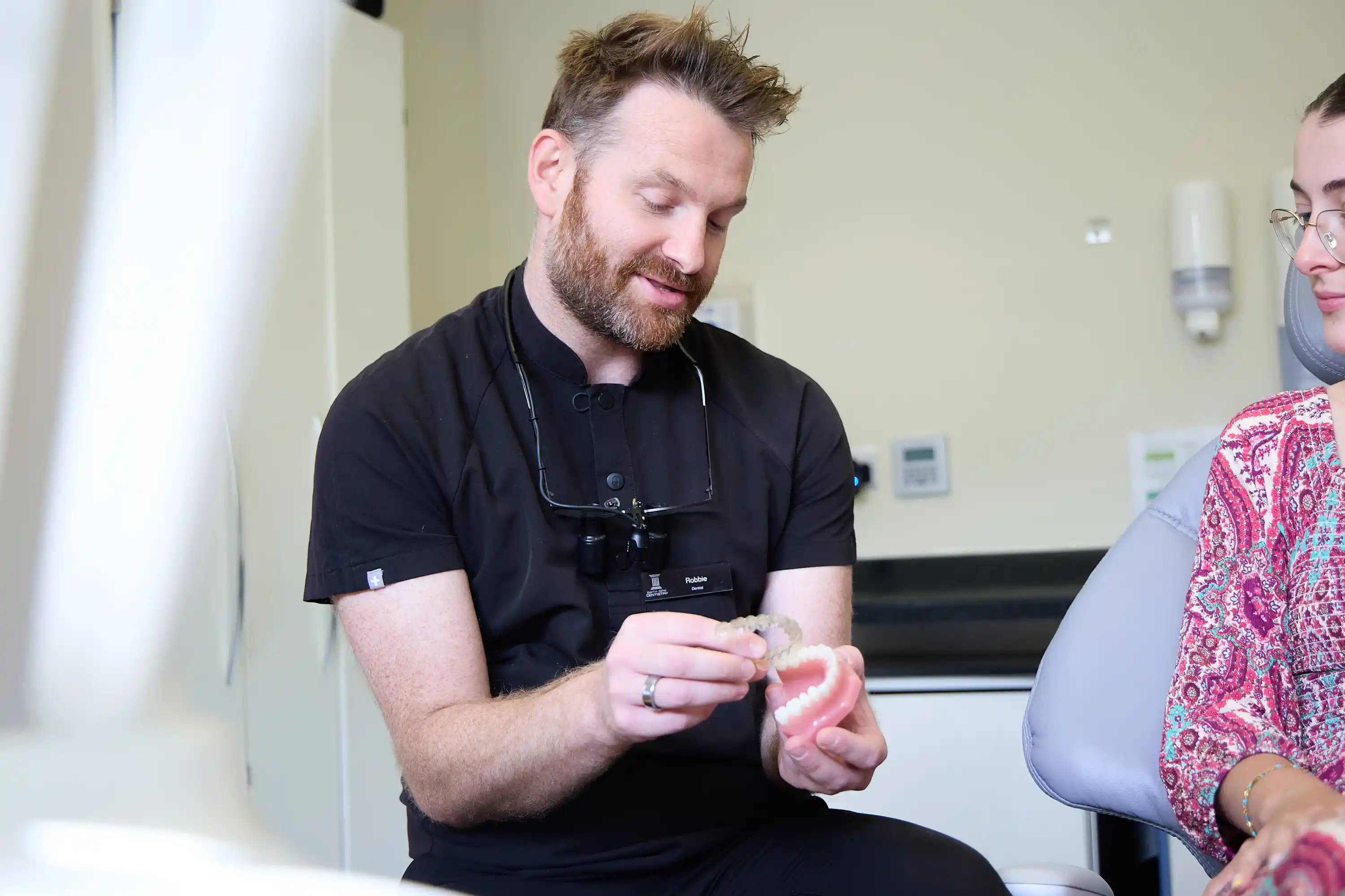 Dentist explaining a dental aligner using a tooth model during a consultation at Bath Spa Dentistry.