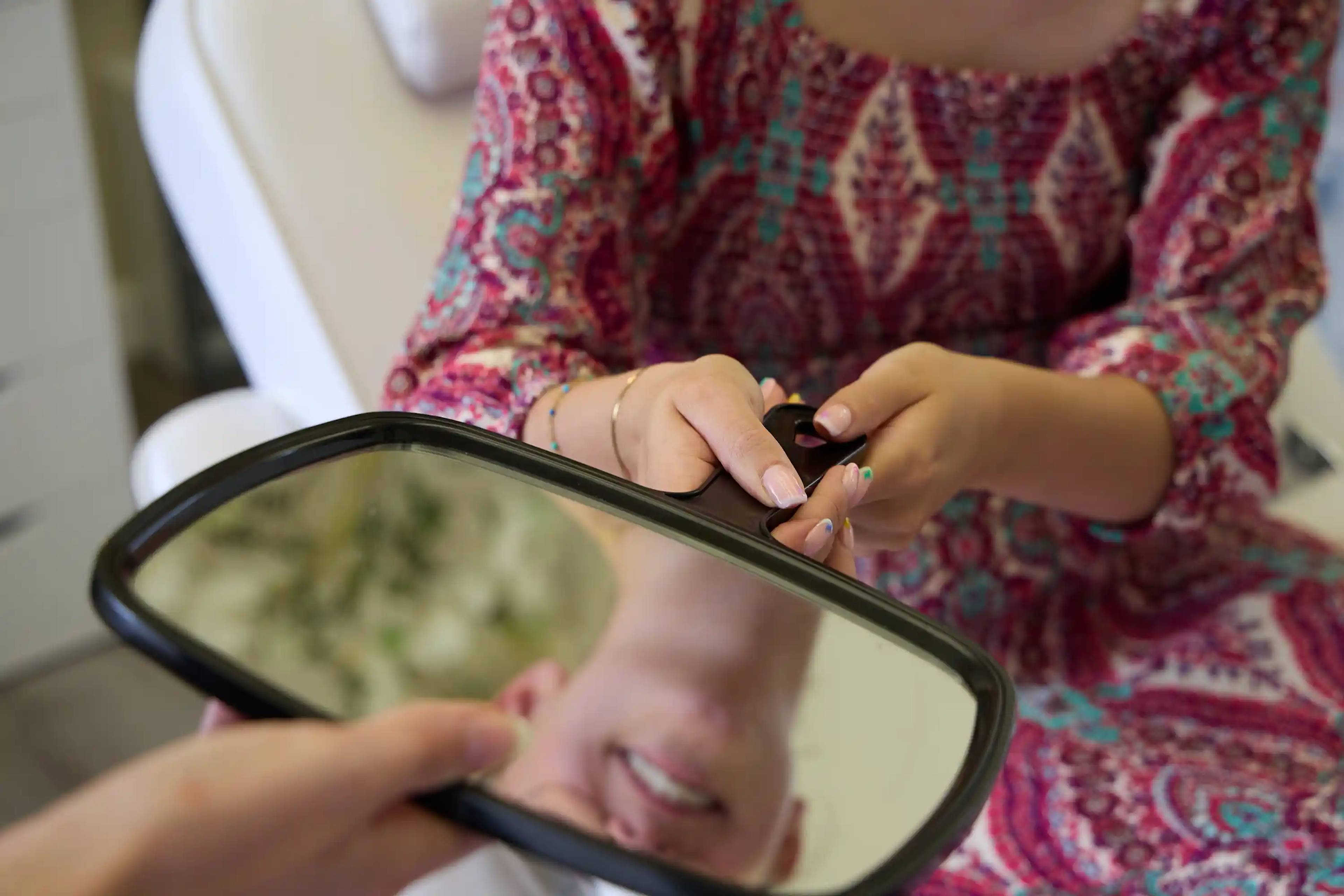 Patient using a handheld mirror to review their smile during a dental consultation at Bath Spa Dentistry.