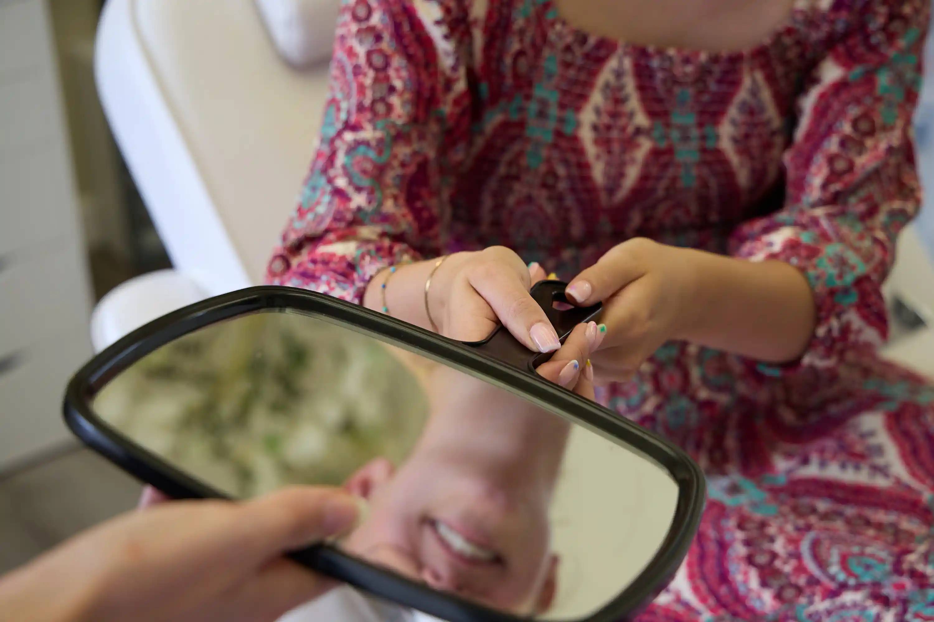 Patient using a handheld mirror to review their smile during a dental consultation at Bath Spa Dentistry.