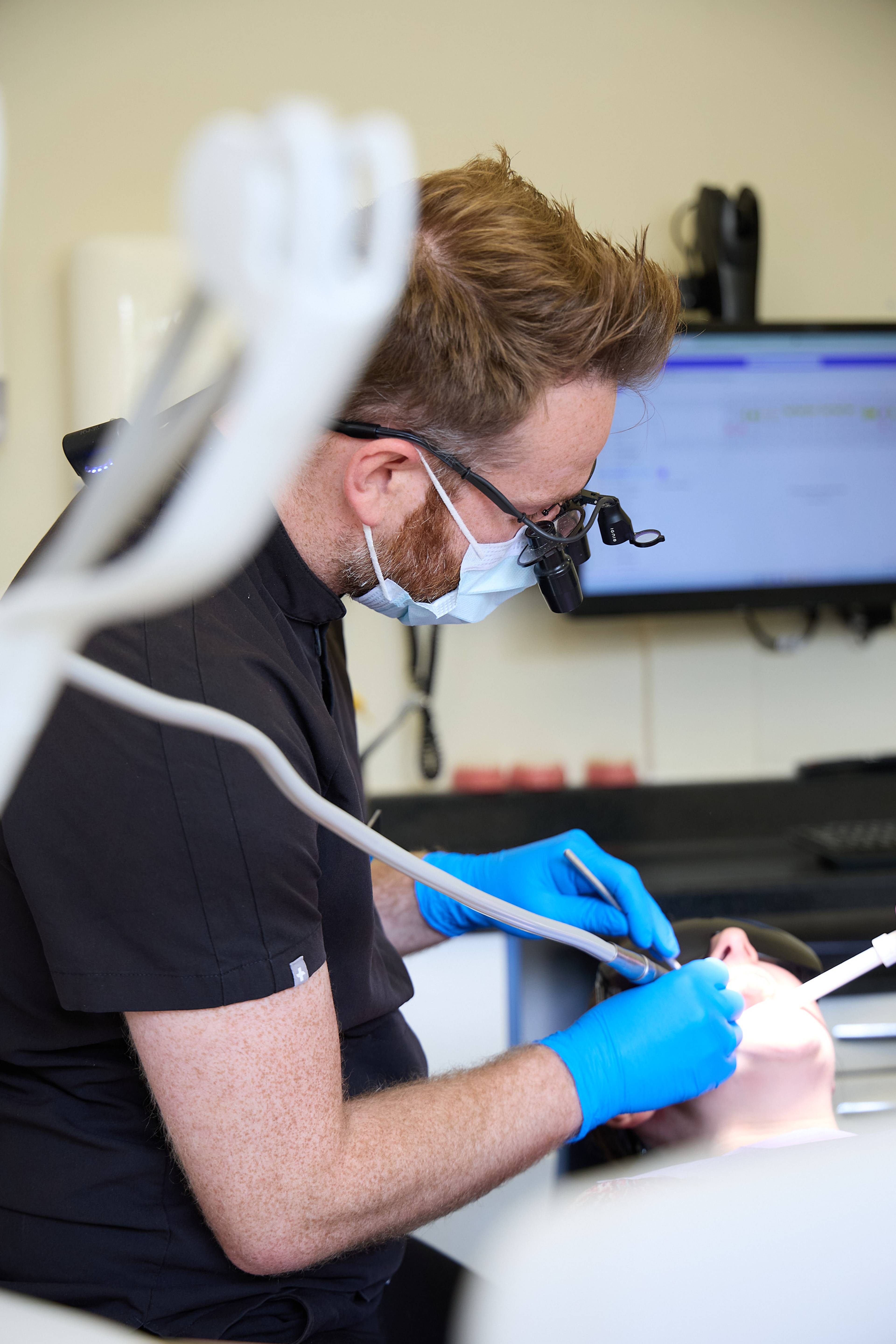 Dentist performing a detailed dental examination using magnification loupes and clinical instruments at Bath Spa Dentistry.