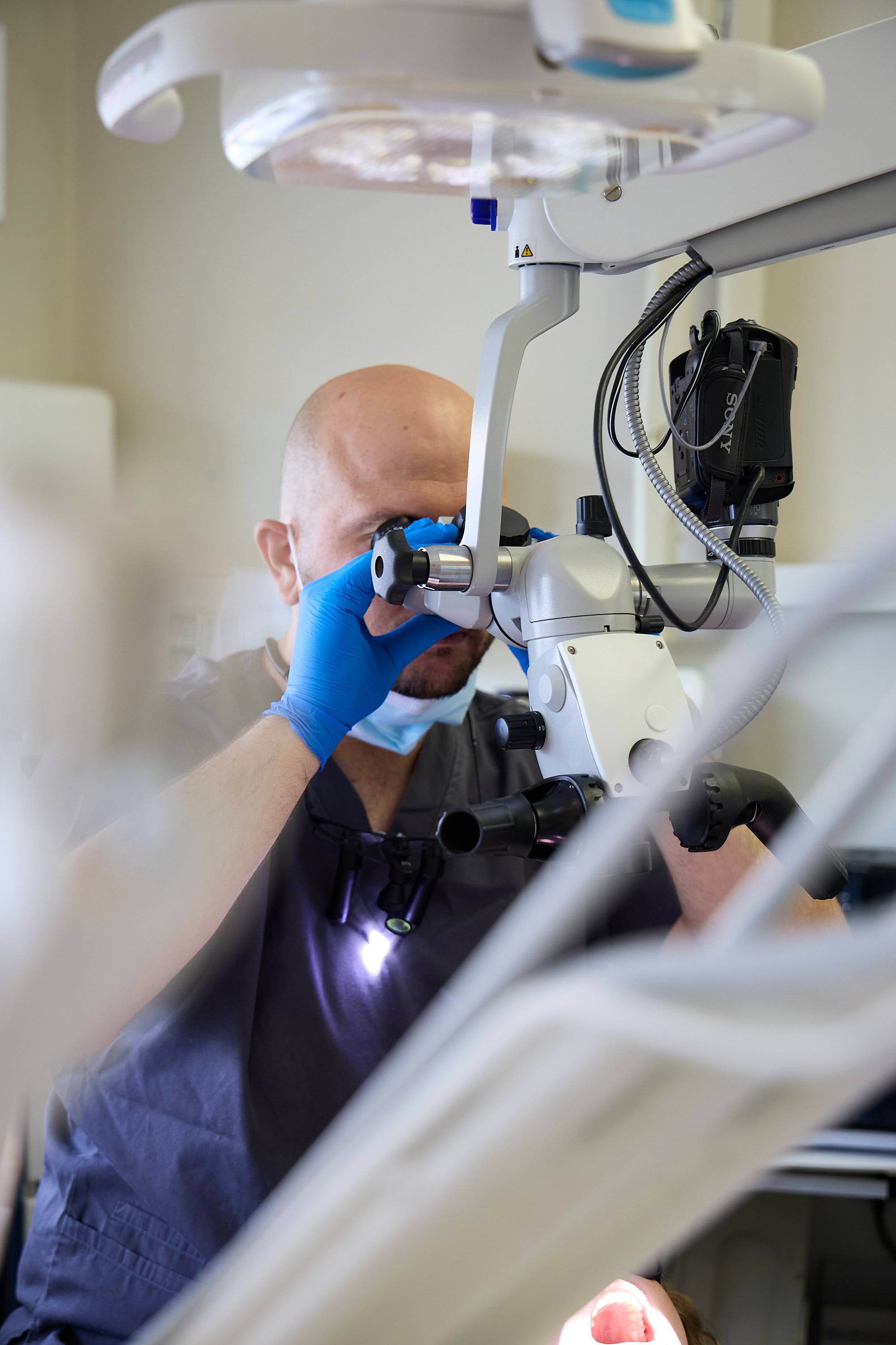 Dental professional using a dental microscope to perform a precise examination and treatment at Bath Spa Dentistry.
