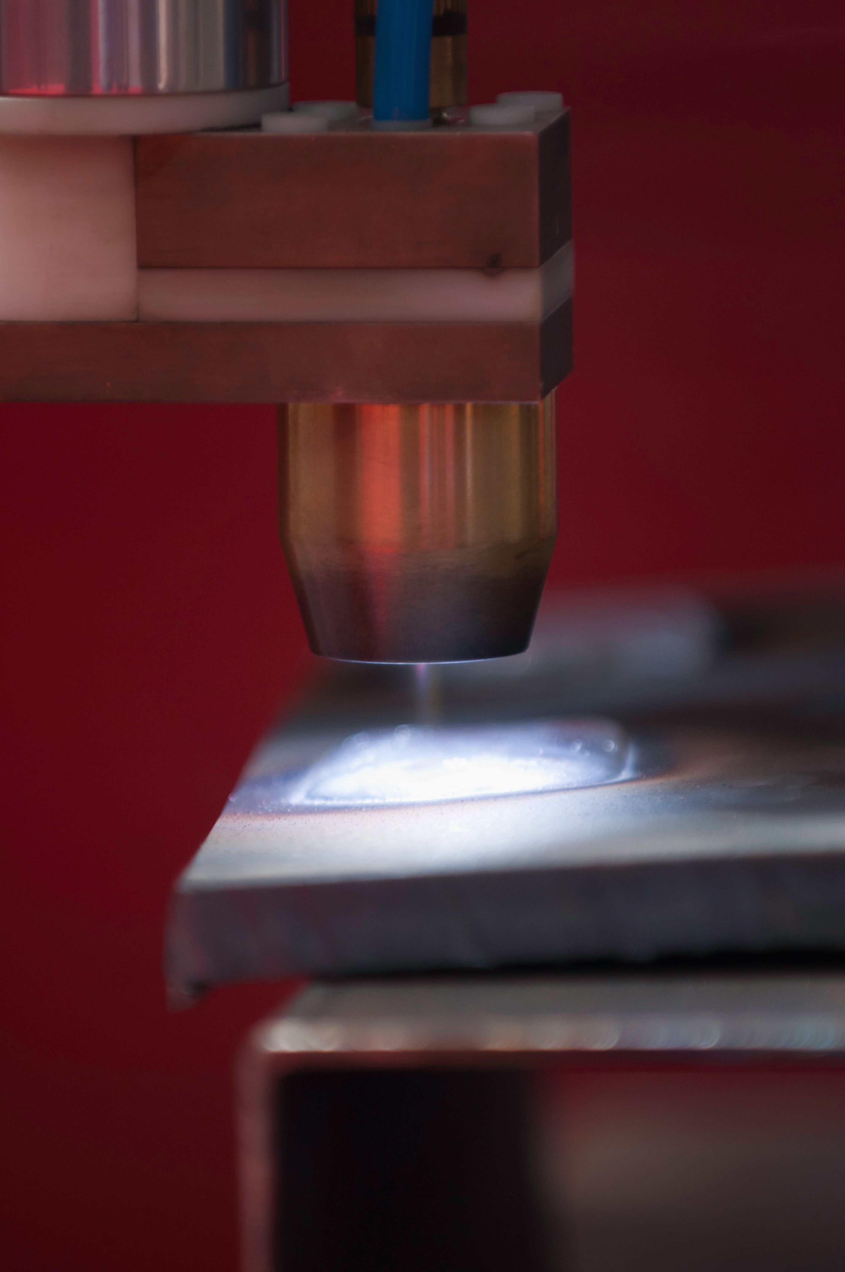 Machine-mounted torch working on a metal joint, labelled plasma welding by the stock contributor.