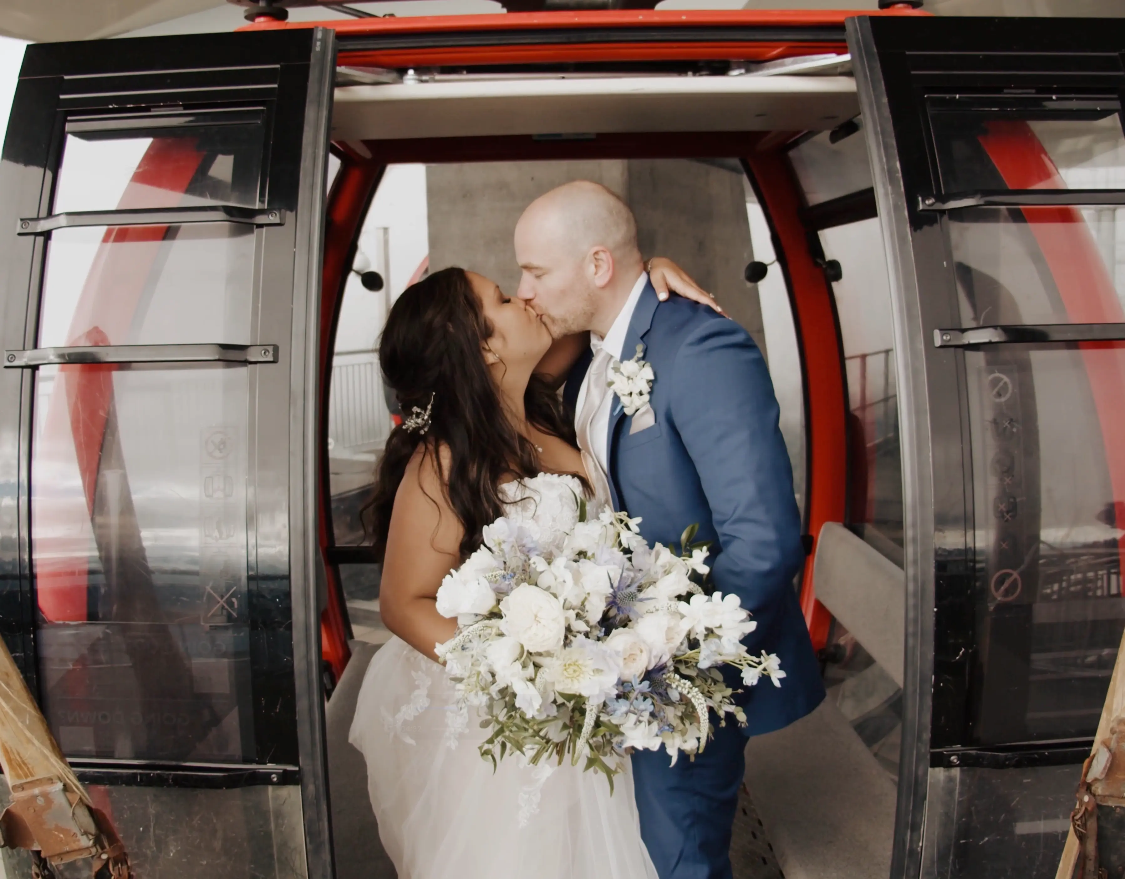 Monica + Jamie pose and kiss in the entrance to the gondola