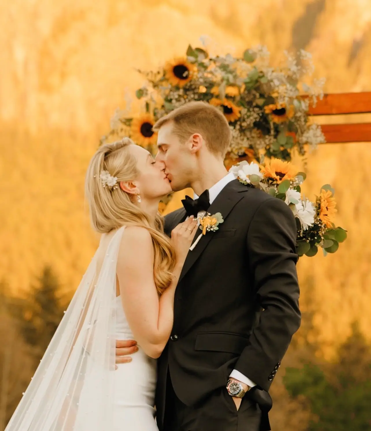 Lauren and Andrew pose and kiss in front of their arbor