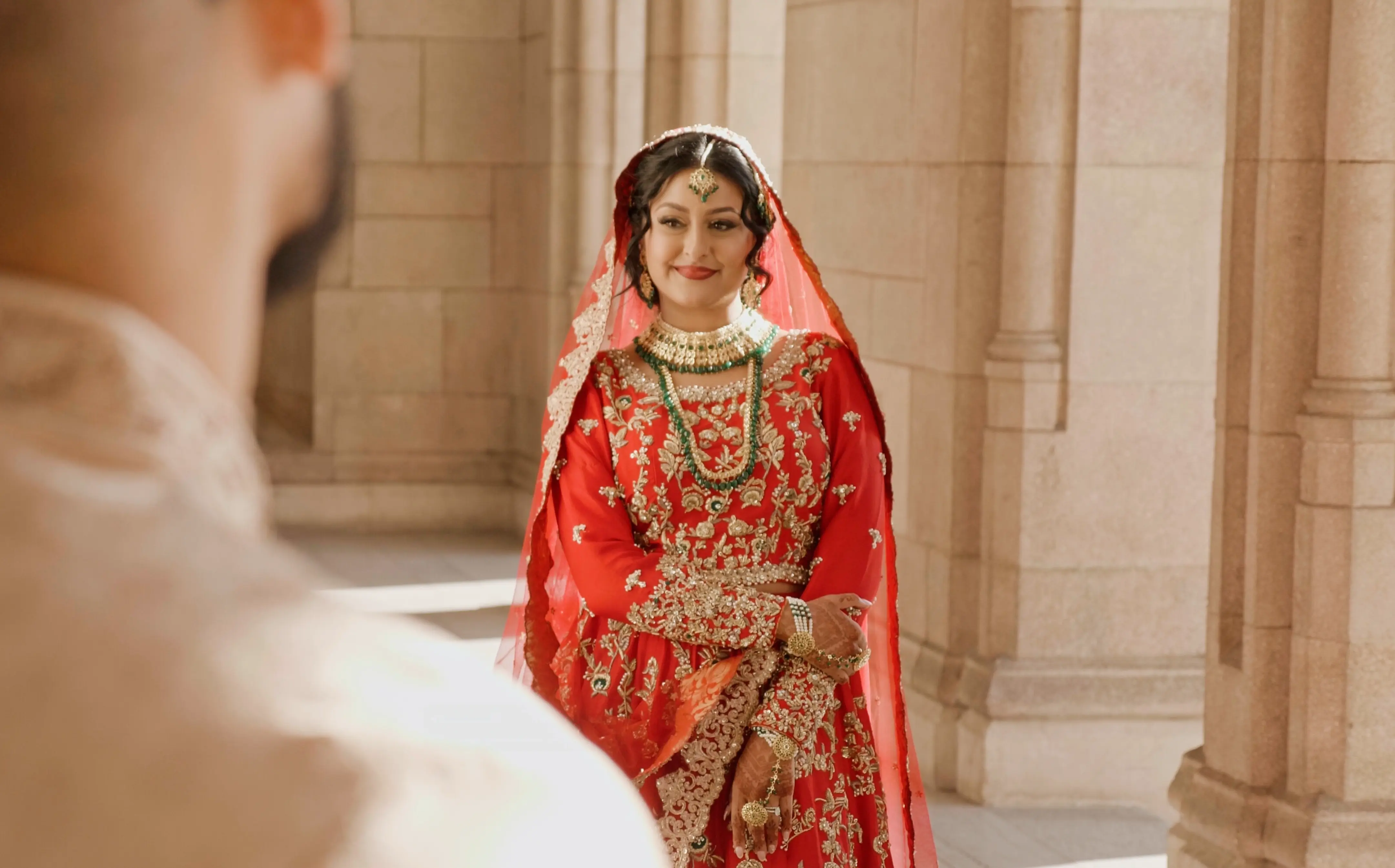 Daniyah stands in a traditional wedding gown and smiles at Sameer