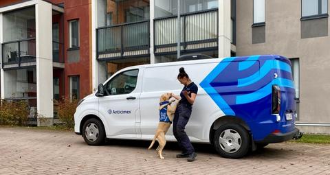 Lutikkakoira ja koiranohjaaja iloisina Anticimexin auton edessä.