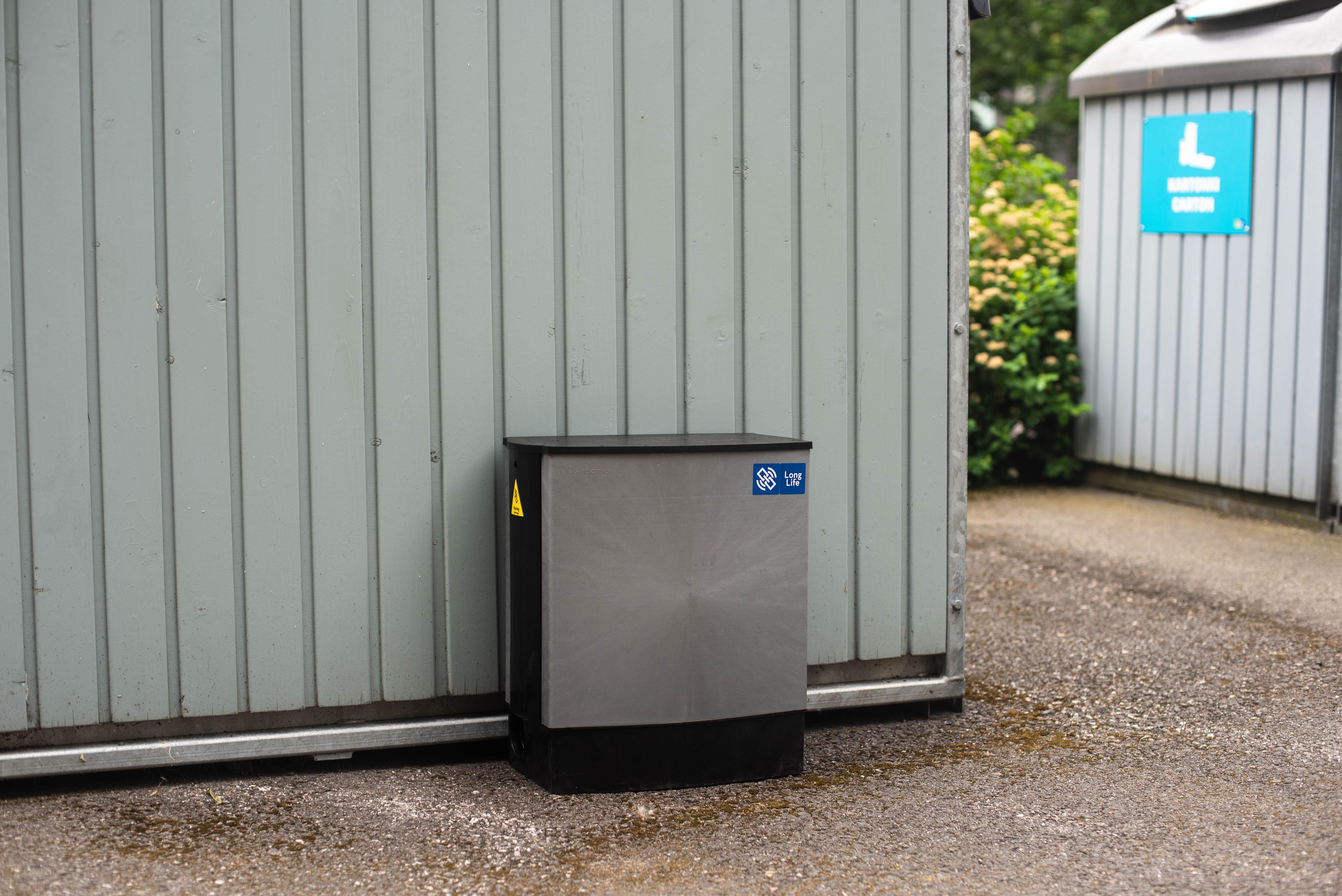 Anticimex Smart Box -jyrsijäloukku maassa seinän vieressä.