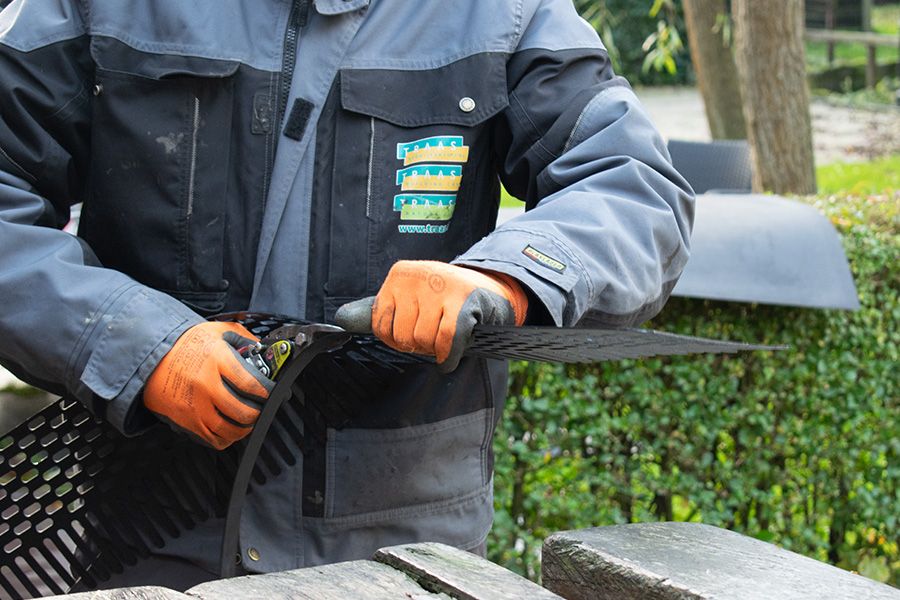 Person in work gloves working on a black grate.