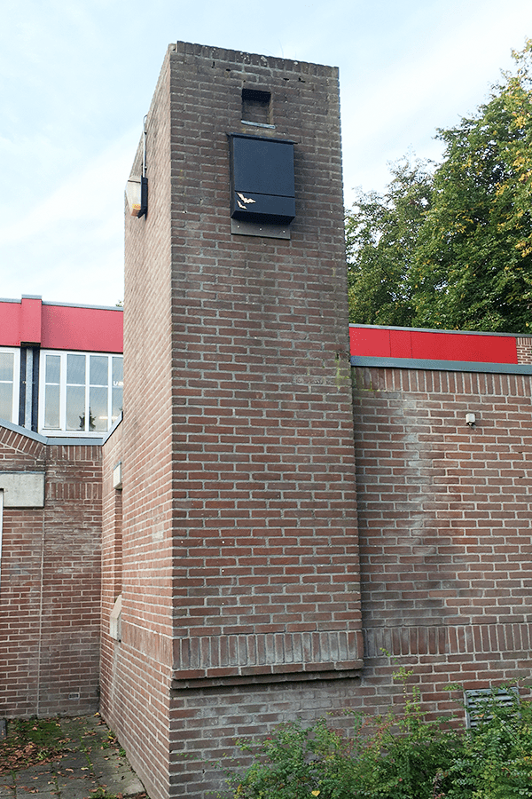 A black bat box mounted on a tall brick building.