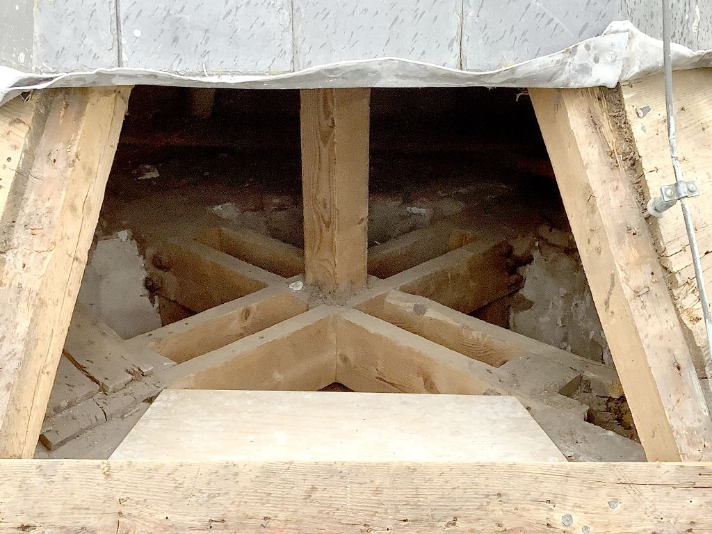 Exposed wooden structural framing with central cross-bracing.