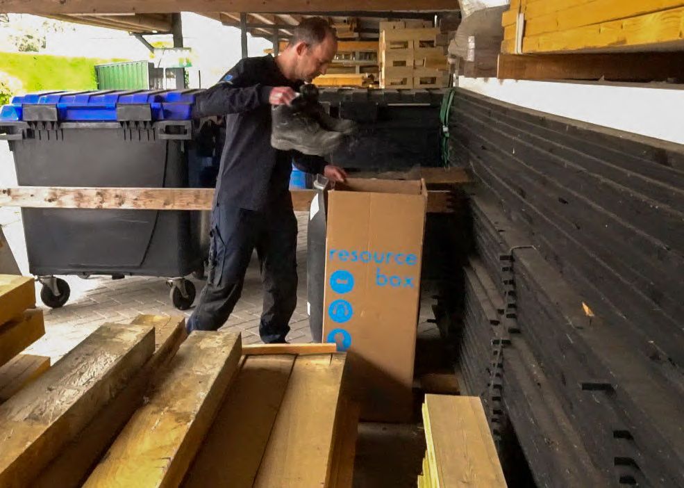 iemand gooit werkschoenen in de recyclebox voor PBM's