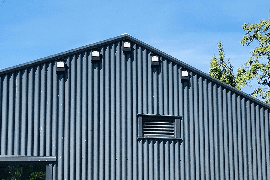 Dark corrugated metal gable end with five lights and a louvered vent.