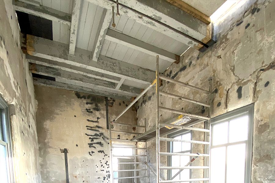Unfinished room with exposed ceiling beams, rough walls, and a metal scaffolding unit.